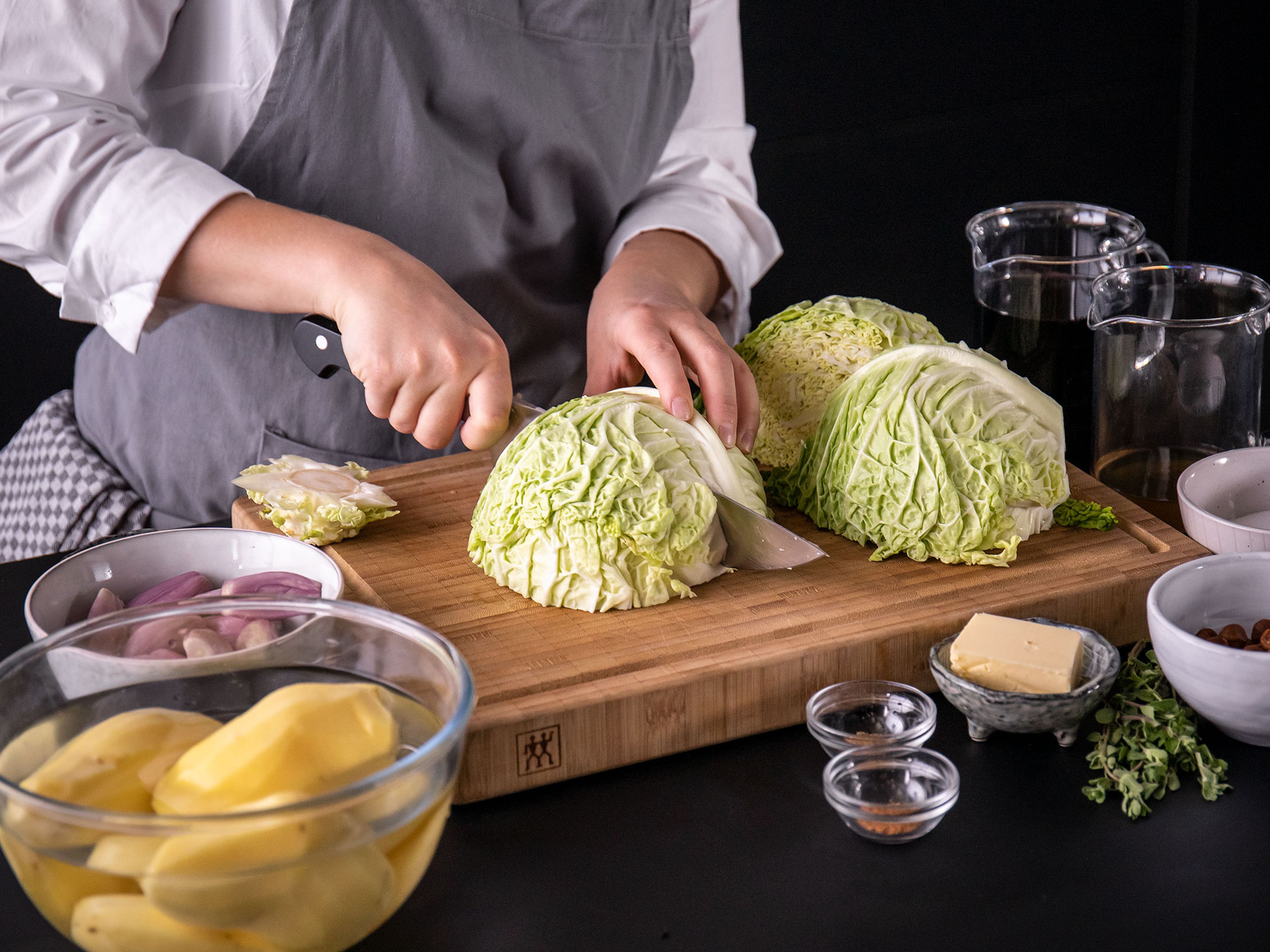 Core, quarter, and cut savoy cabbage into thin slices. Peel and dice the potatoes. Mince some shallots, and thinly slice the rest. Chop hazelnuts.