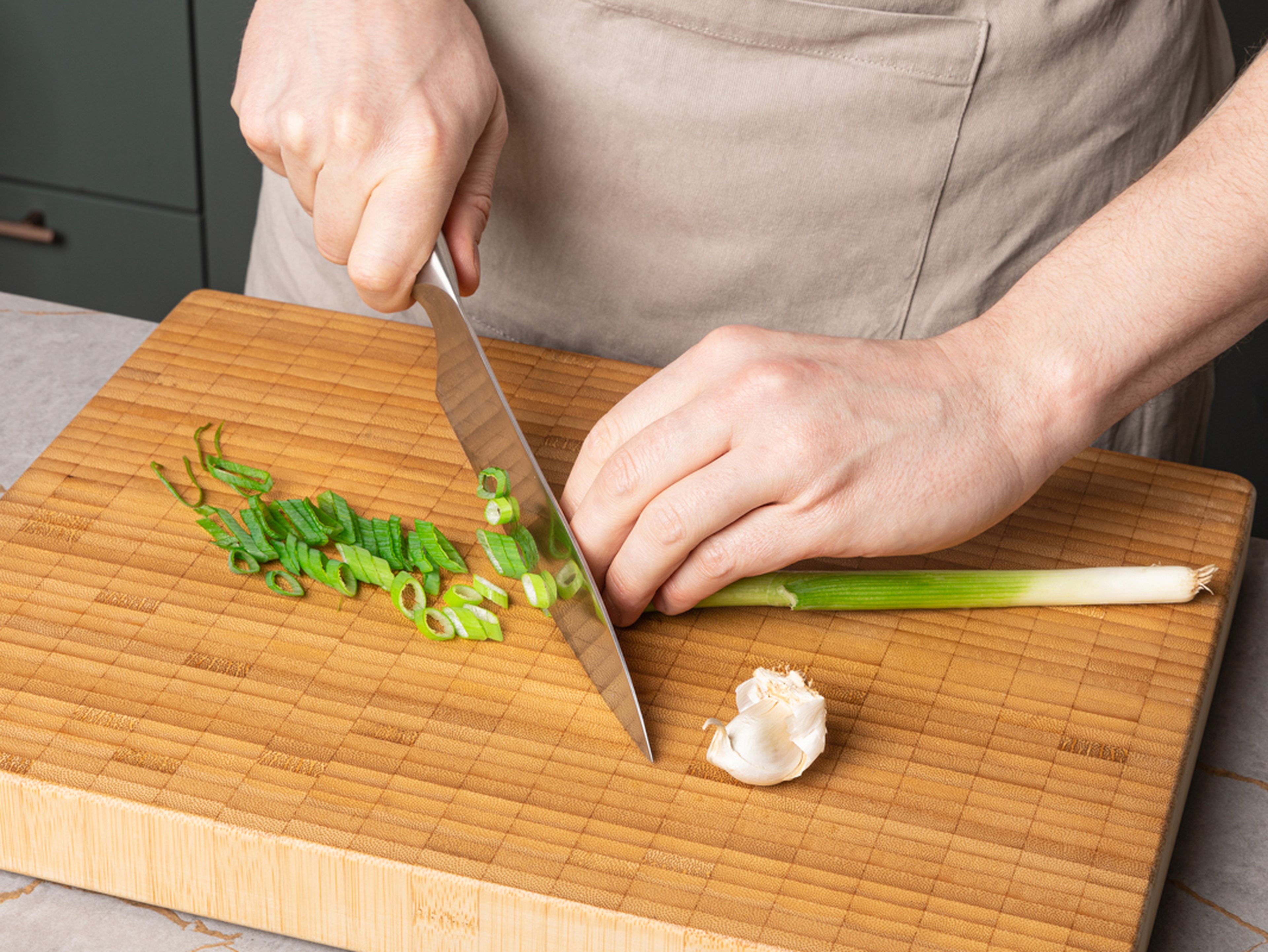 Preheat the oven to 220°C/428°F top/bottom heat (200°C/392°F convection oven). Finely chop the garlic. Separate the white and green parts of the spring onion and cut them into fine rings.