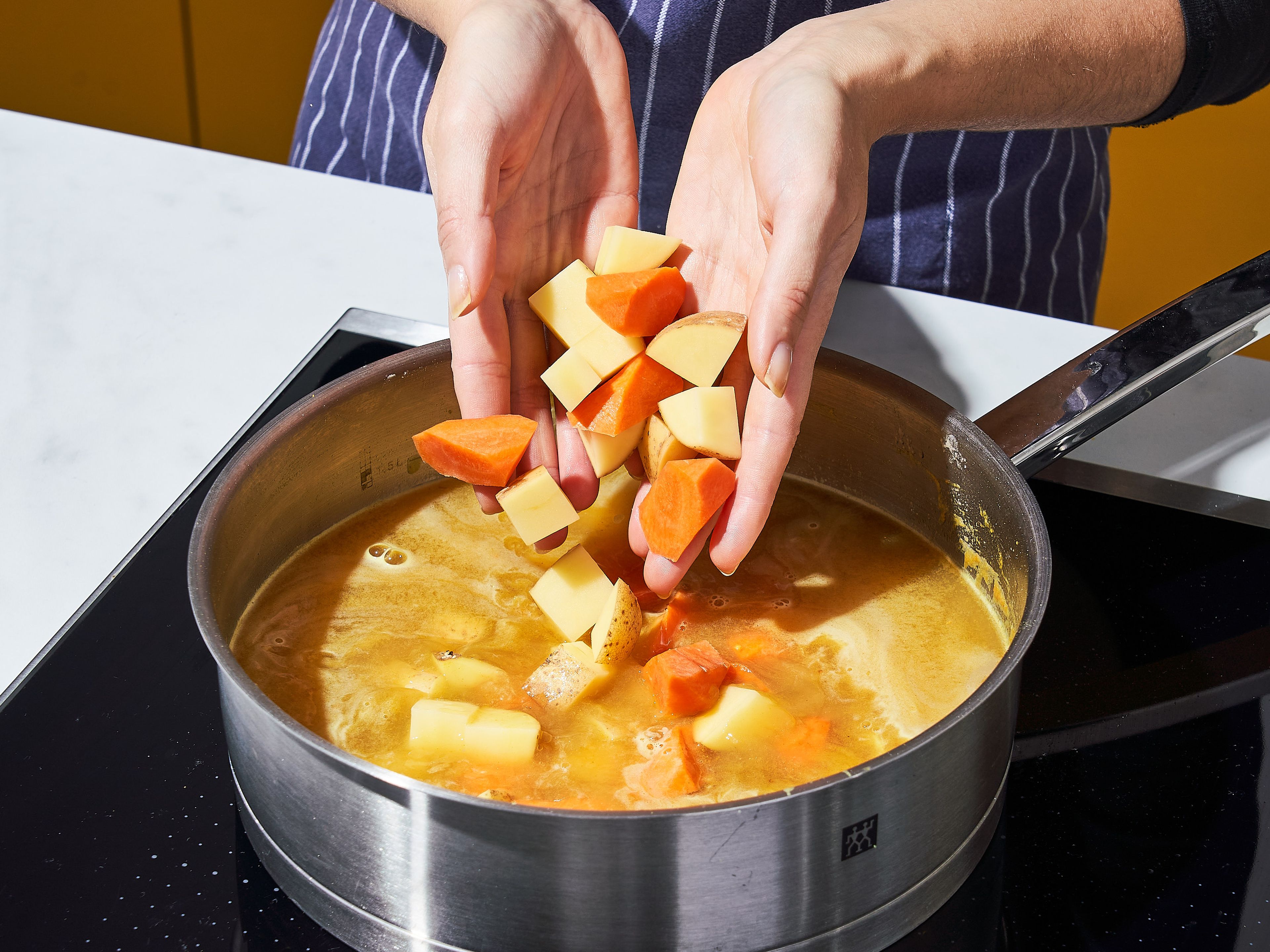 Deglaze with chicken stock and apple juice, then add sugar, vinegar, soy sauce, potatoes, and carrots to the pot. Let simmer over low heat for approx. 30 min., or until the sauce is thickened but still pourable and the vegetables are tender all the way through. Season with salt to taste.