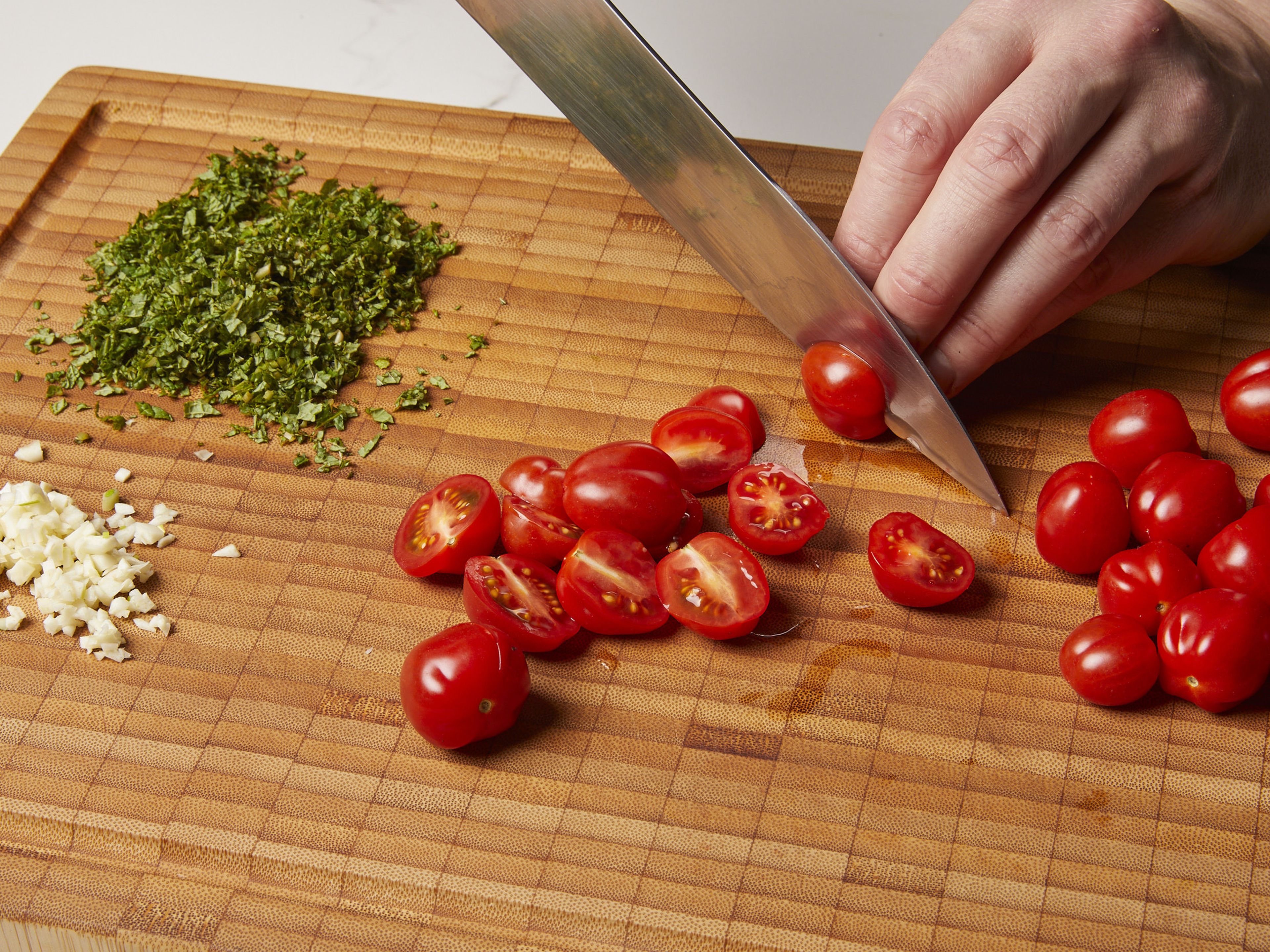 Peel and finely chop garlic. Then halve cherry tomatoes and finely chop mint. Wash lemon and finely grate 1 tsp of zest, then juice it.