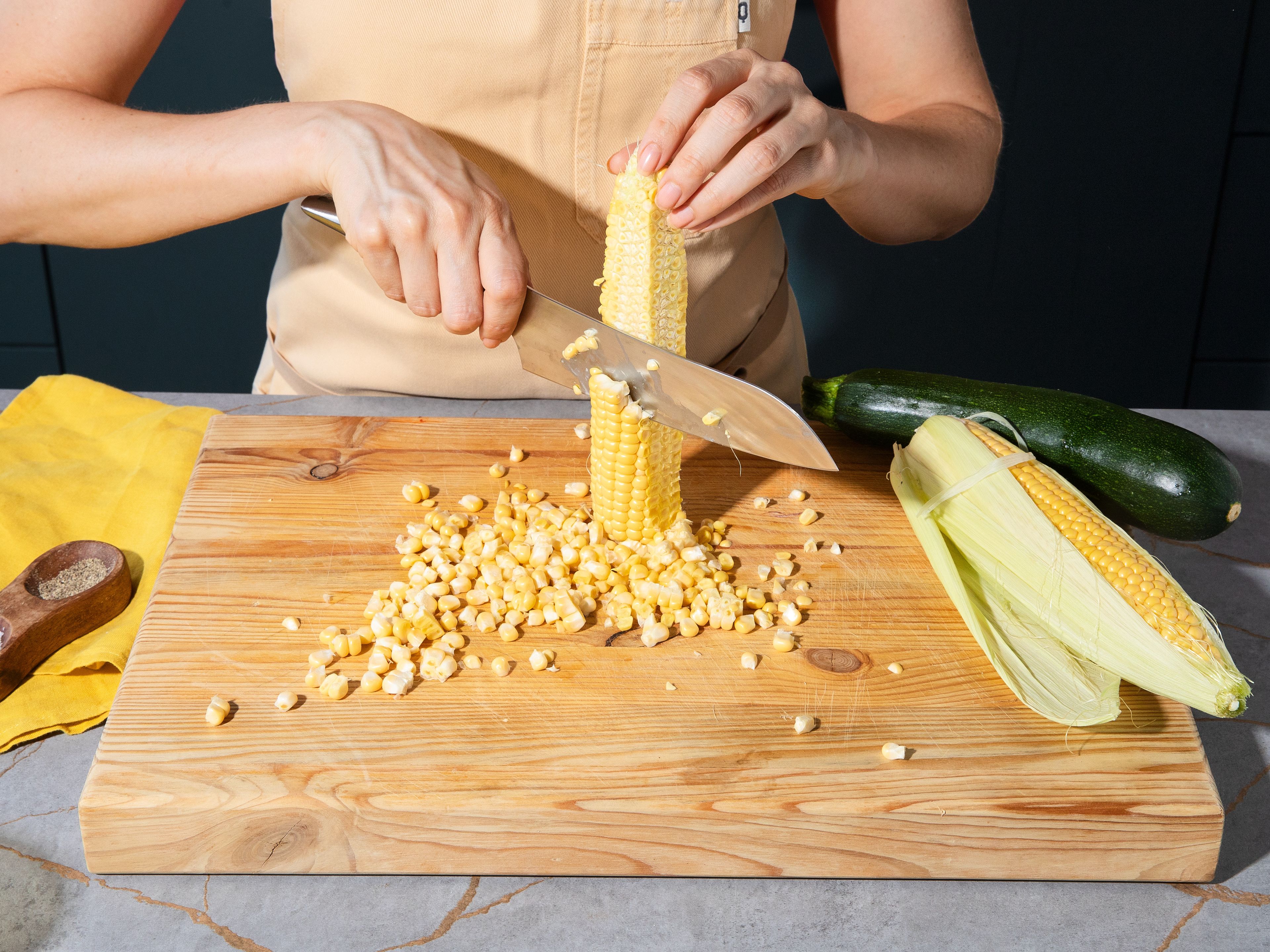 Die Maiskörner mit einem Messer vom Kolben schneiden. In einer sehr heißen großen Pfanne in Olivenöl anrösten, bis sie goldbraun und gebräunt sind. Die Butter dazugeben und den Mais darin kurz schwenken, bis er glänzt und leicht nussig riecht. Mit Salz würzen und in der Pfanne beiseitestellen. Währenddessen Zucchini mit einem Gemüseschäler in dünne Scheiben schneiden, leicht salzen und ebenfalls beiseite stellen.