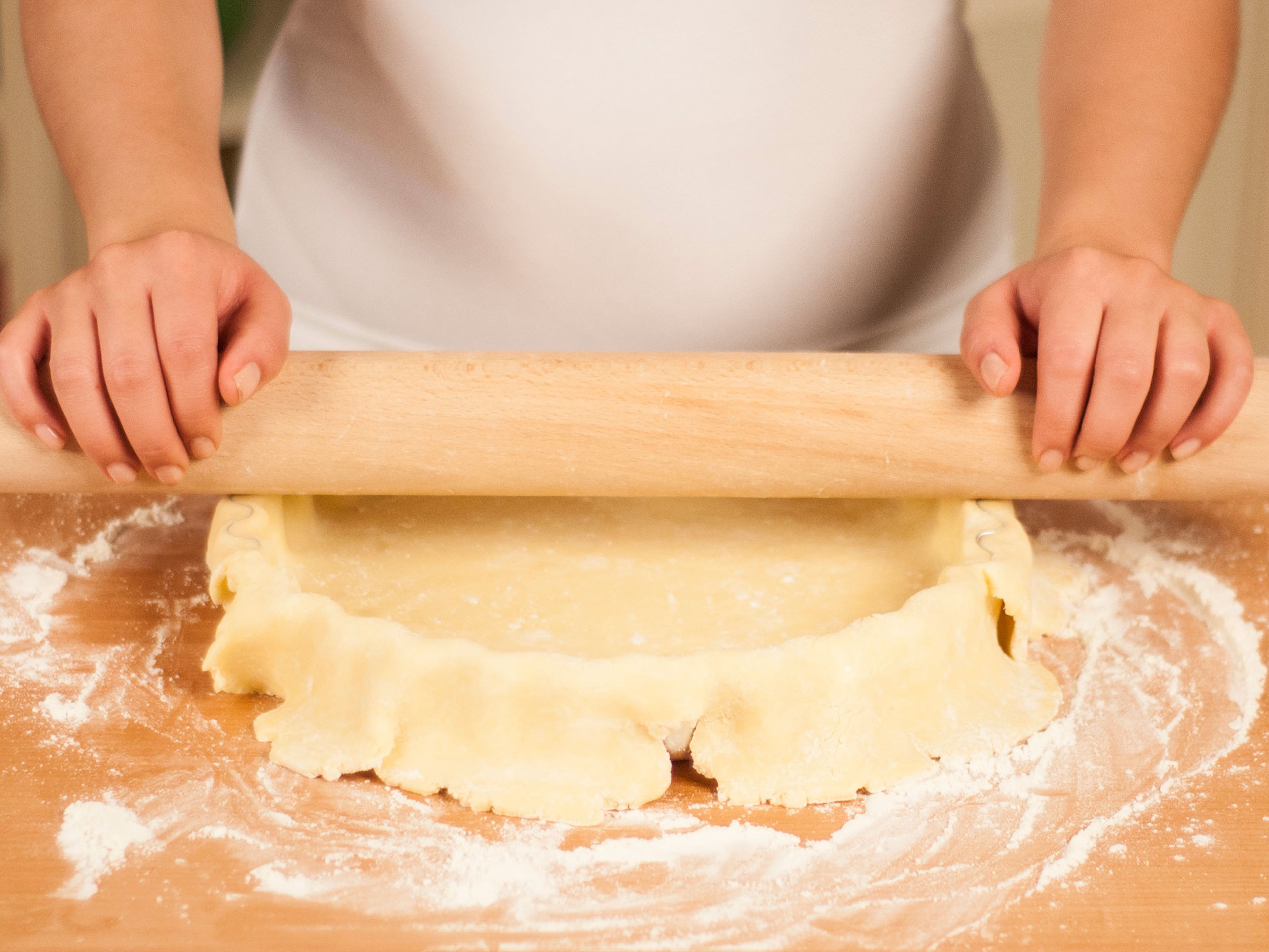 Cut off overhanging dough by rolling the rolling pin over the edges of the tart dish.