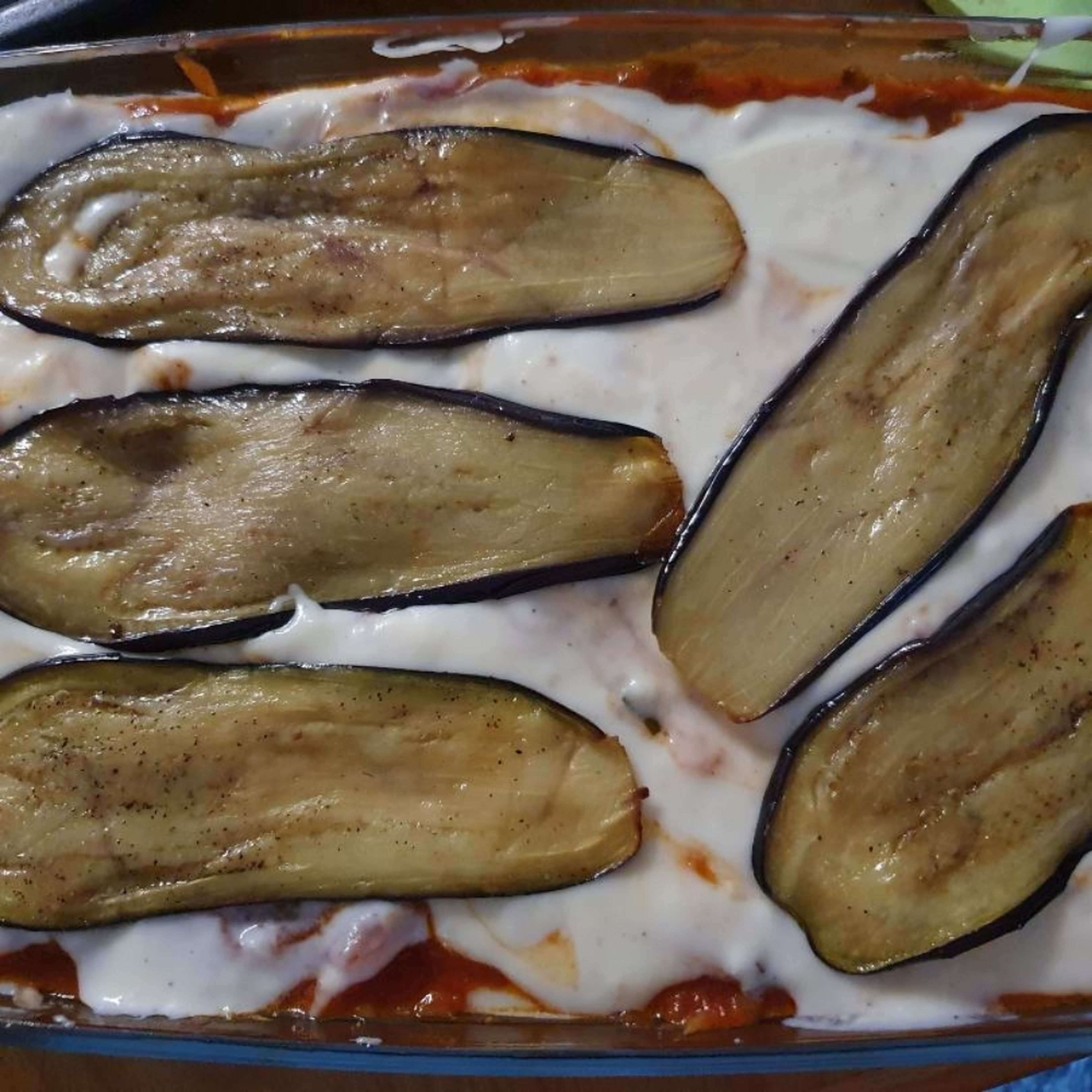 Backofen bei Ober/Unterhitze auf 190 °C vorheizen. Auberginen etwas salzen und pfeffern. In einer Auflaufform wie folgt schichten: Bechamelsauce, Lasagneplatten, Auberginen, Tomatensauce. Solange wiederholen, bis alle Zutaten aufgebraucht sind. Nach den letzten Lasagneplatten die Bechamelsauce und die Auberginenscheiben schichten.