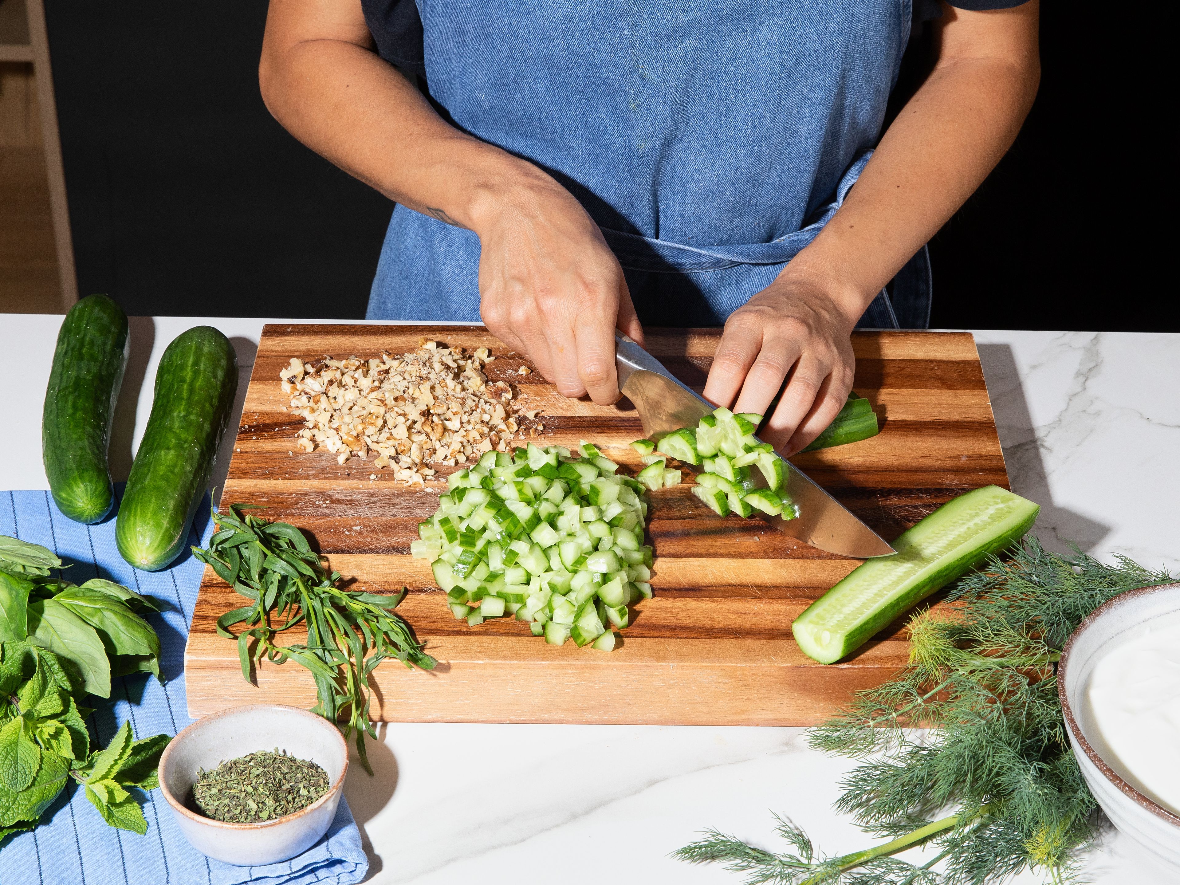 Place the bread on an oven rack and dry out at 150°C for approx. 15 min. Dice cucumbers into small cubes. Finely chop herbs and walnuts. Mix yoghurt with water, dried mint, and season with salt and pepper.