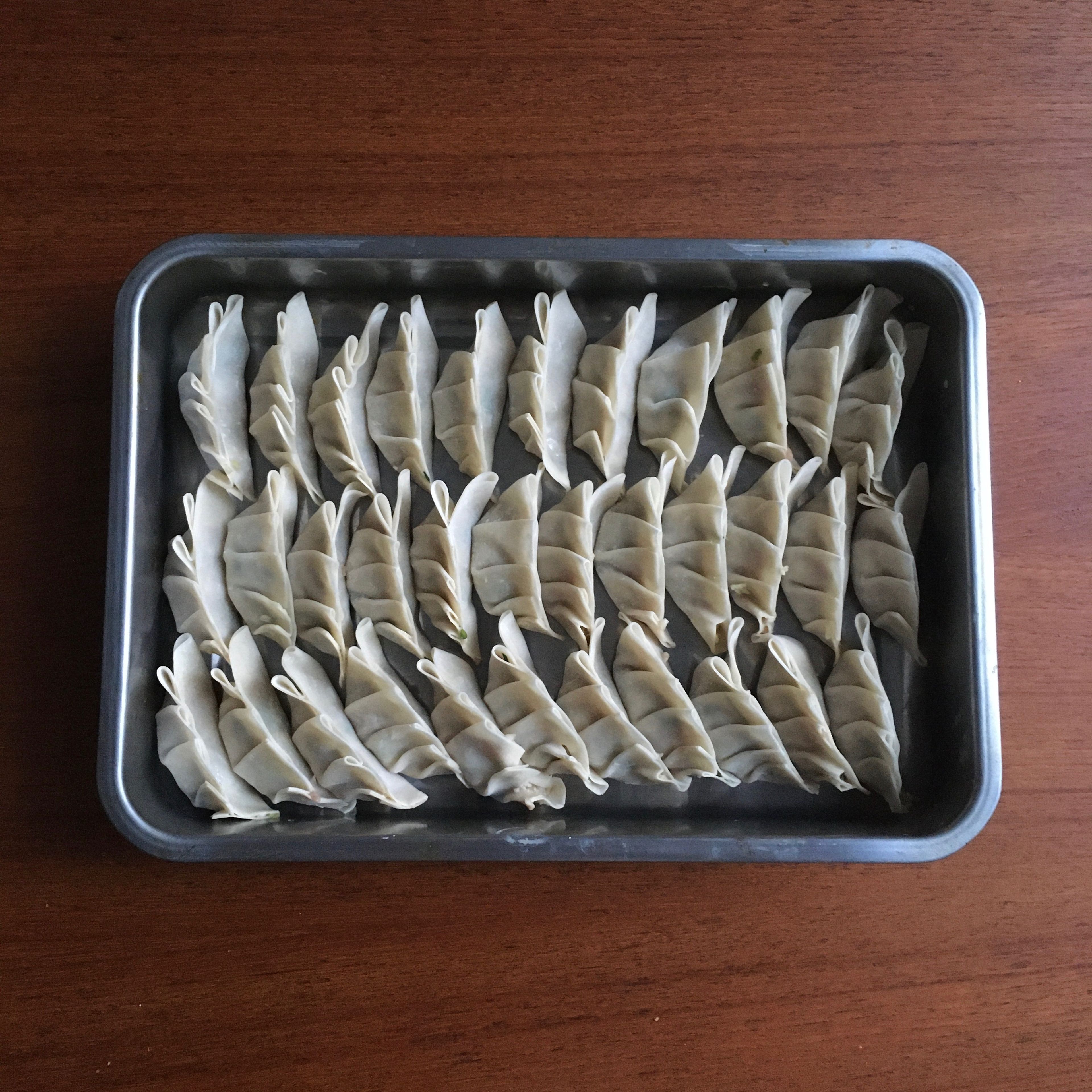 Place finished gyoza on a tray, or plate, as you continue filling the rest of the wrappers.
