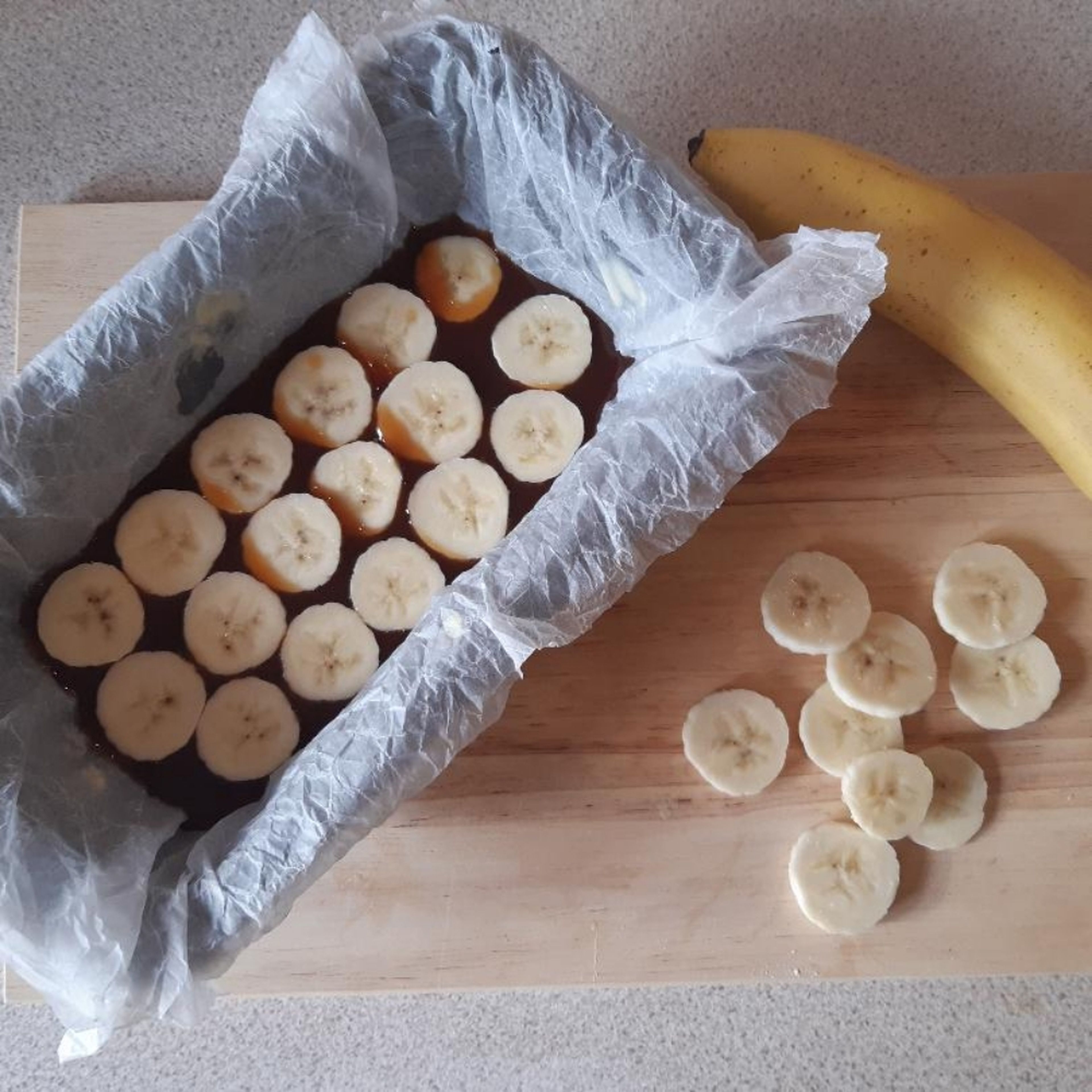 Whilst the caramel cools a little, line the loaf tin with parchment paper and then chop the ripe banana into circles. Pour around two thirds of the caramel into the bottom of the lined tin and layer the banana on top. Set the rest of the caramel aside for serving later.