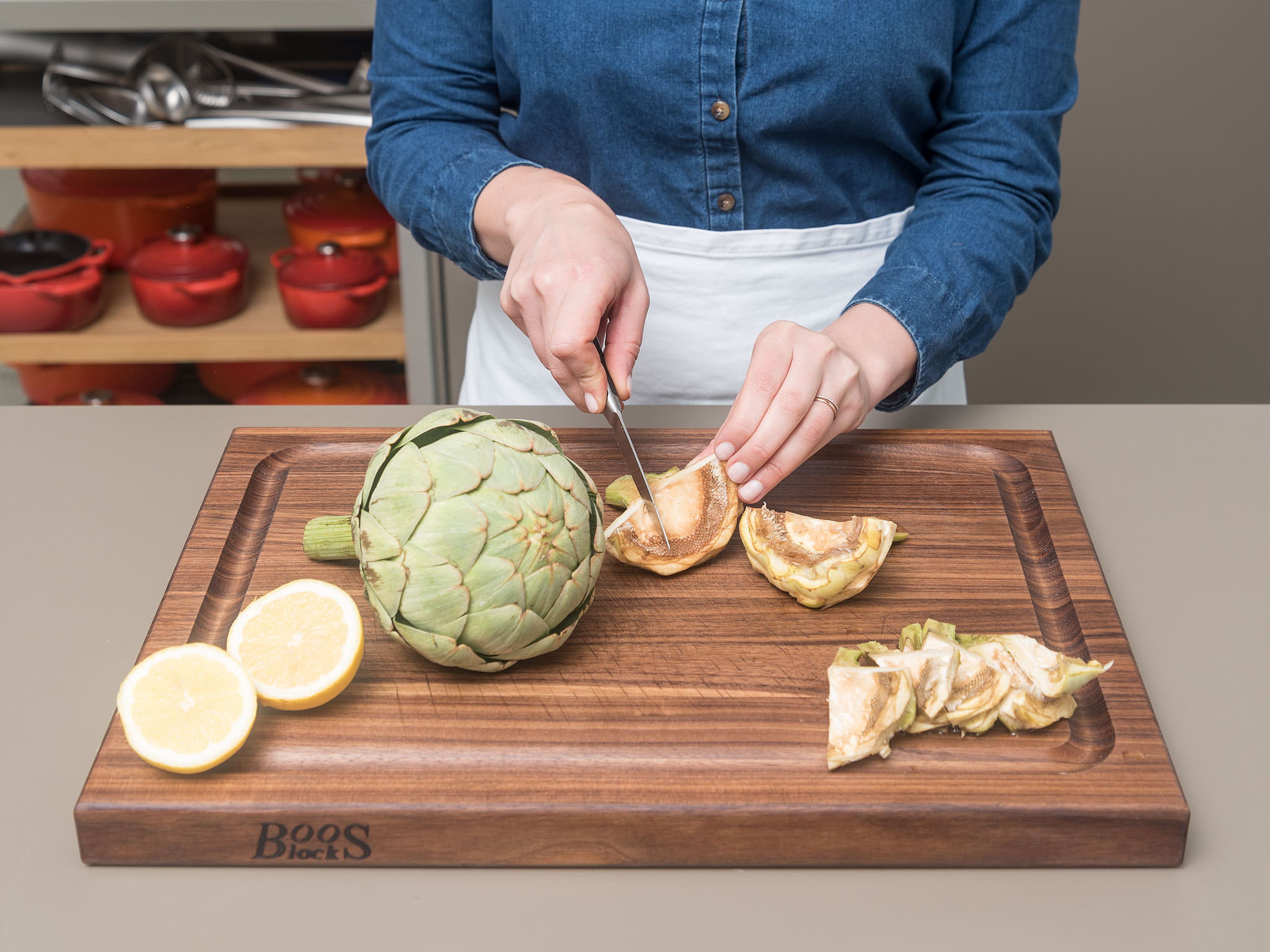 Preheat oven to 190°C/375°F. Add juice of half of lemon  to a large bowl of water. Remove outer leaves of artichokes until you reach the pale yellow center, periodically dipping the artichoke into the lemon water to prevent browning. Peel base and stem of artichoke, then slice off the top third of the artichoke leaves. Slice in half, then use a spoon to scoop out the fuzzy center and purple prickly leaves. Slice halves into thirds. Peel and crush garlic, slice other half of lemon, and halve tomatoes.