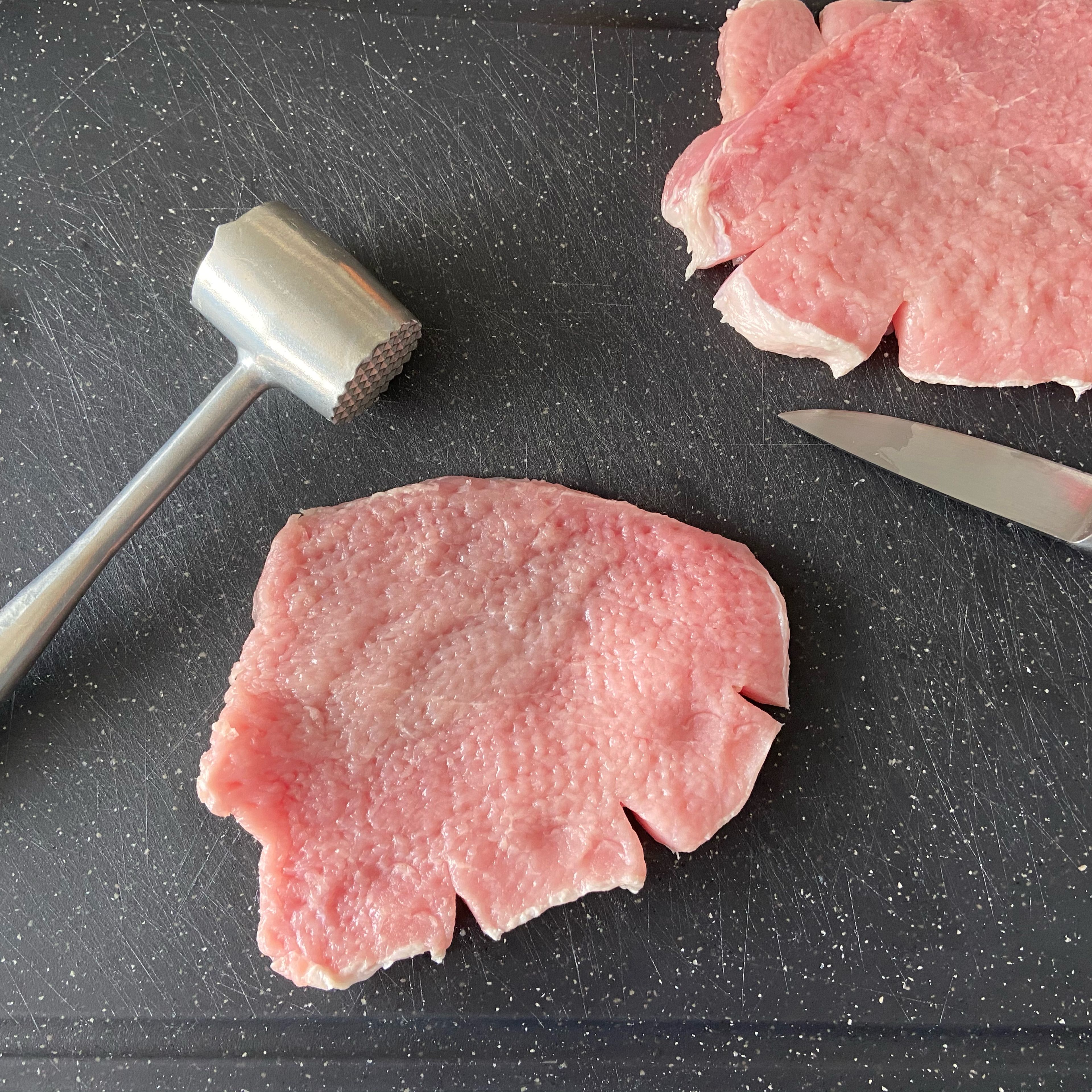 Cut some small slits in the fat side of the pork cutlet and then use a tenderizer to flatten the cutlet into an even thickness. It should be about 1/2 inch or less. The slits are to prevent shrinkage and curling when the cutlet cooks. 
