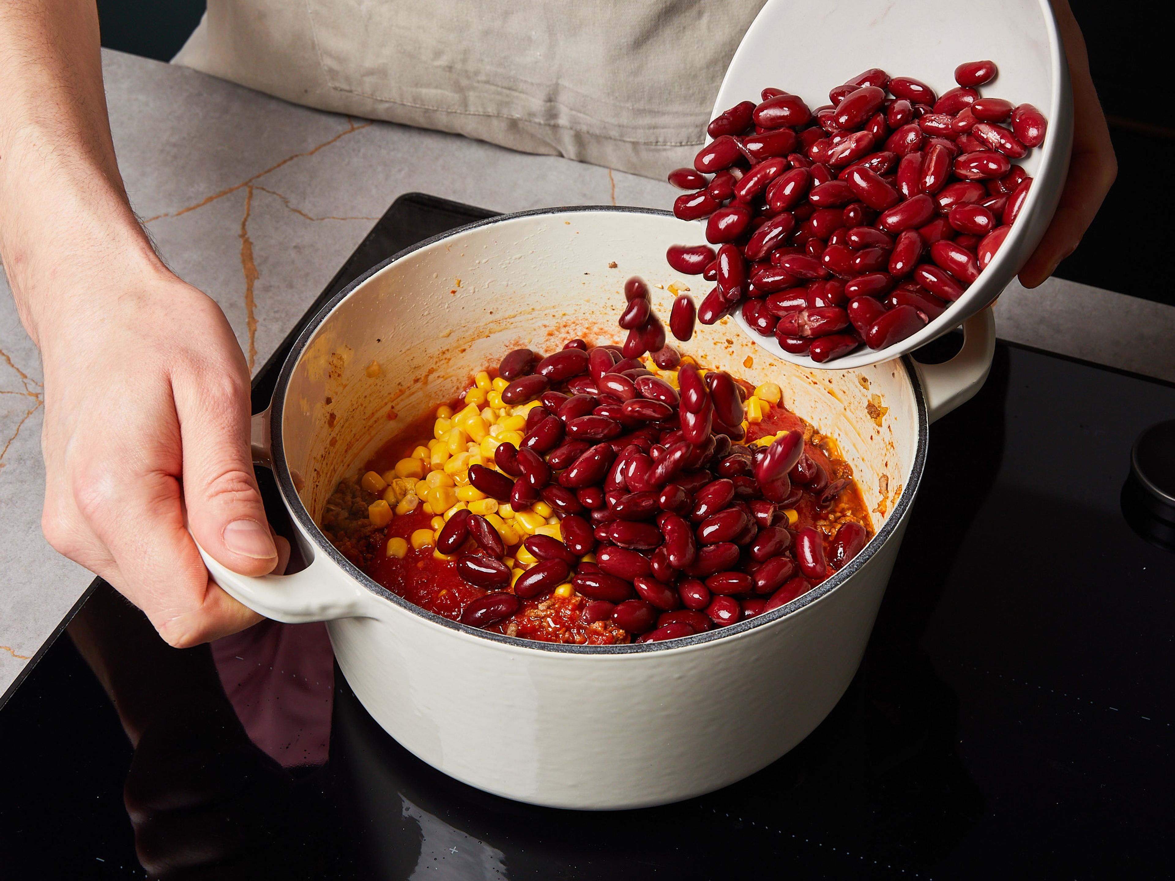 Add canned crushed tomatoes, sweet corn, kidney beans, and the chopped red pepper. Stir well to combine.  Leave to simmer for approx. 15—18 min. over low-medium heat. Stir occasionally. Season to taste with sugar, salt, and pepper. Serve with aromatic rice and sour cream.