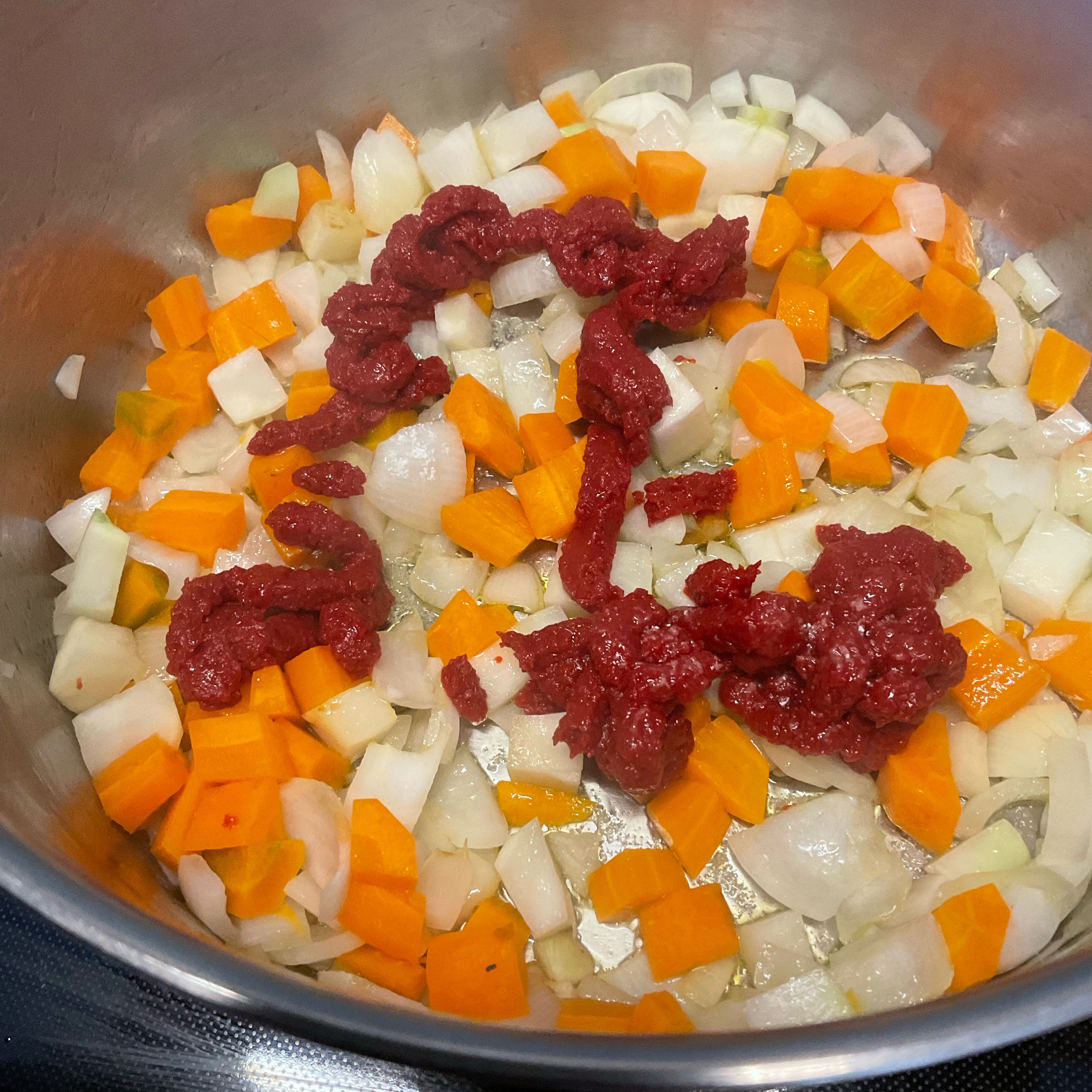 Wenn das gewürfelte Gemüse etwas angebraten ist, die halbe Tube Tomatenmatk zugeben und dieses ebenfalls scharf anbraten. Danach zum karamellisieren mit 2 TL Puderzucker bestreuen.