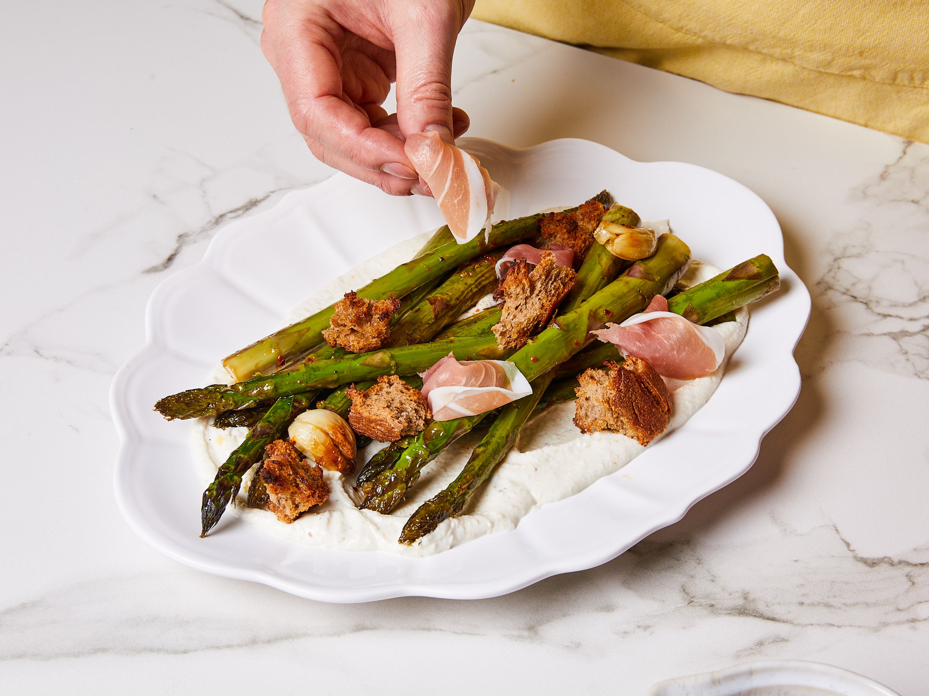 To serve, spread feta mix on a large serving platter or shallow bowl. Place the asparagus on top, drizzle the oil mix on top and spread croutons over it. Tear the prosciutto into pieces and scatter over the dish. Serve warm or at room temperature.