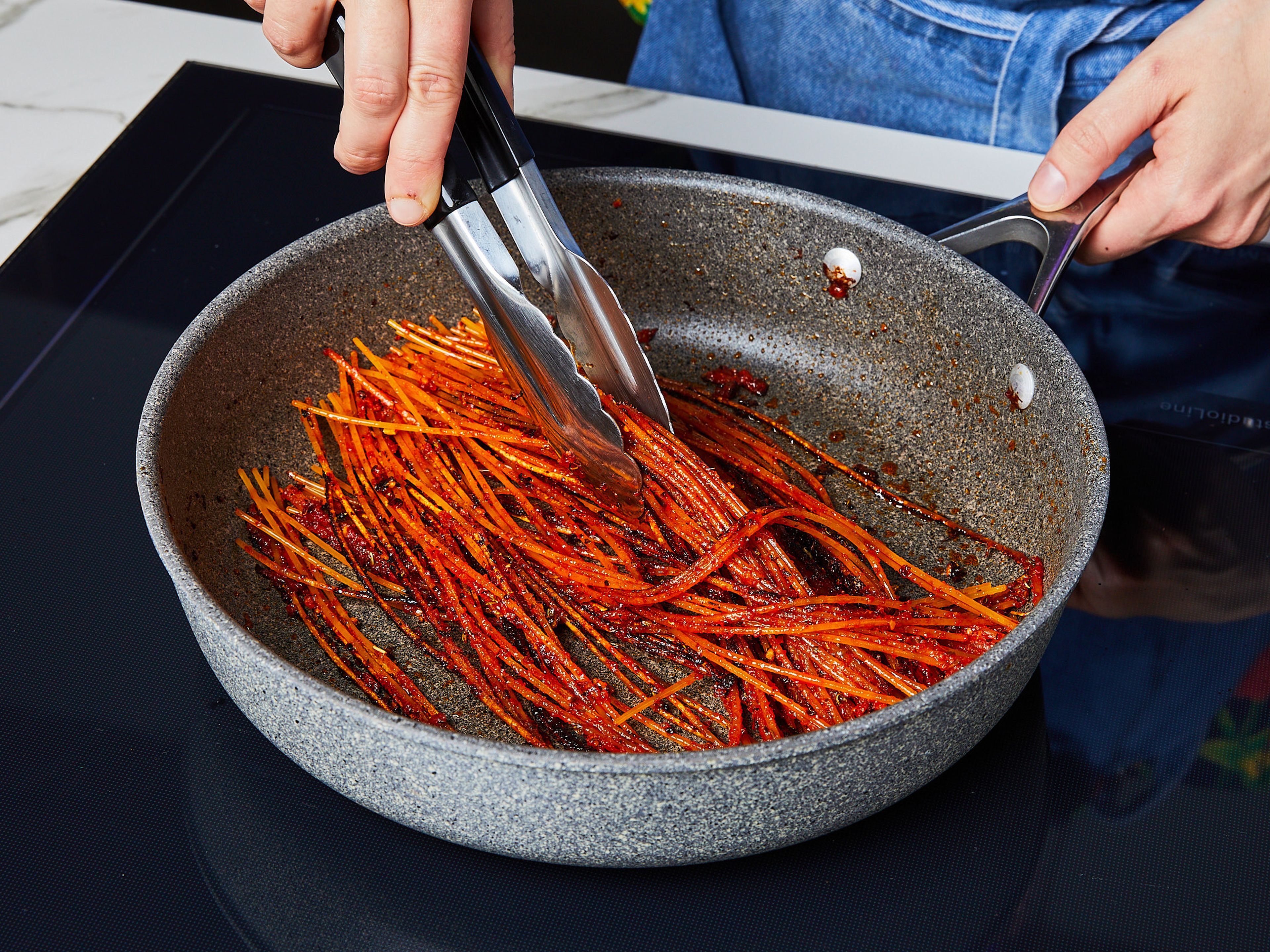 Wenn der Knoblauch goldbraun ist, das Tomatenmark und die Gewürzmischung hinzufügen und ca. 2 Min. köcheln lassen. Dann die Spaghetti dazugeben und ca. 3–5 Min. in der Soße kochen lassen, bis diese karamellisiert und man dunkle, knusprige Stellen auf den Nudeln sieht.