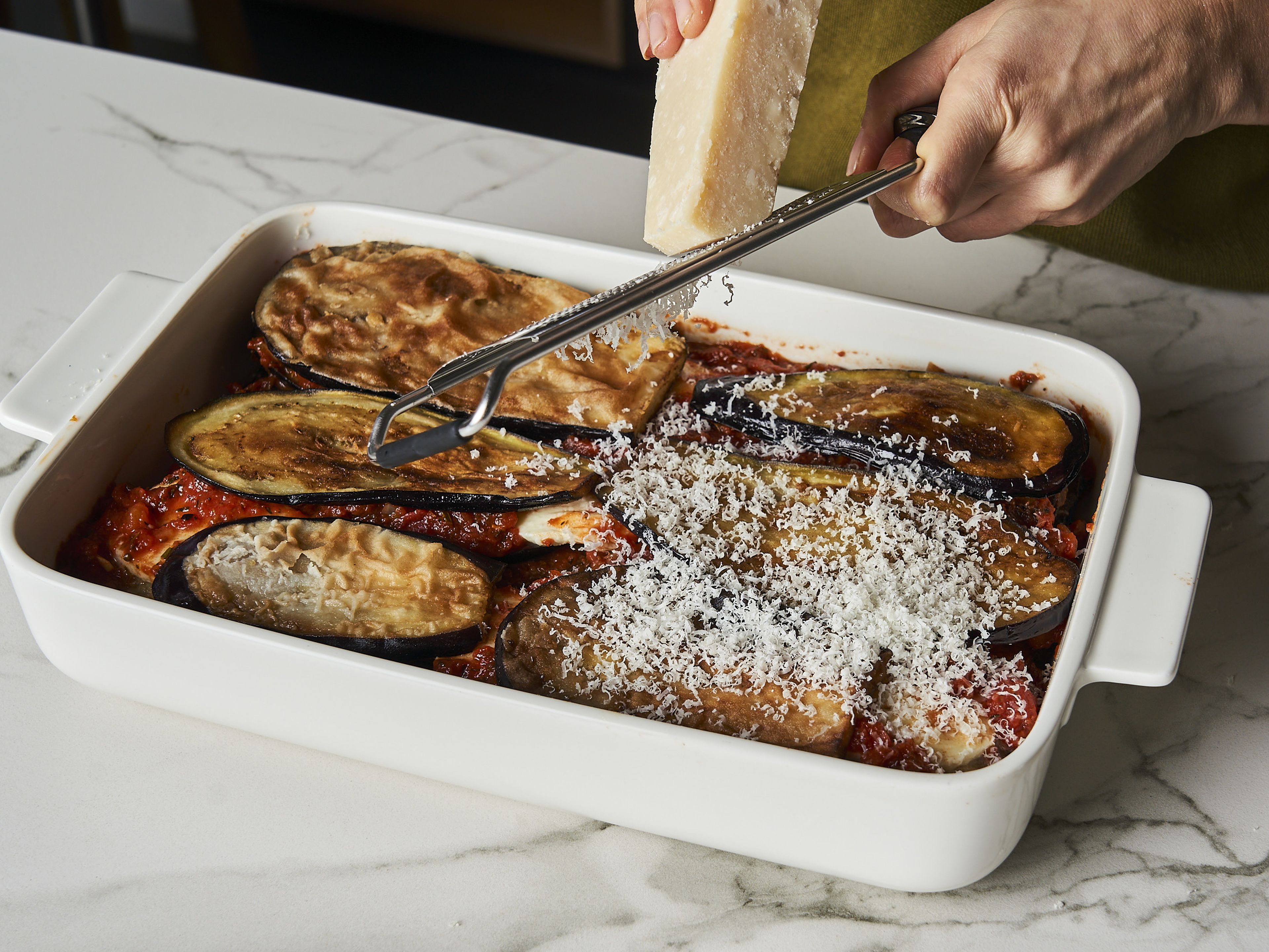 Zum Schluss mit frisch geriebenem Parmesan bedecken. In den vorgeheizten Ofen geben und für ca. 20-25 Min. goldbraun backen. Mit frischen Basilikumblättern garnieren und warm genießen!