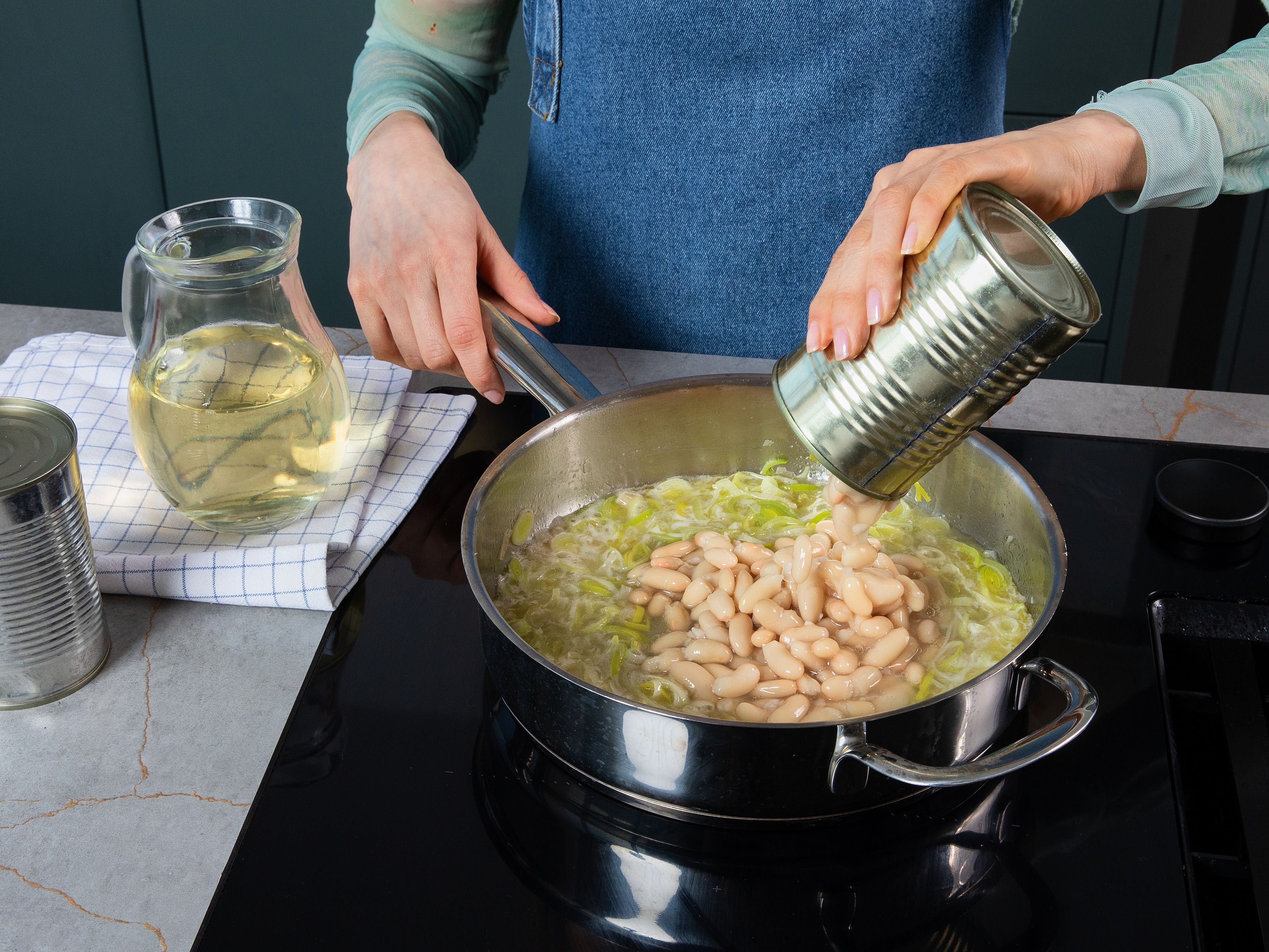 Mit Weißwein ablöschen und ca. 2–3 Min. köcheln lassen, bis der Alkohol verdampft ist. Dann die weißen Bohnen abgießen und noch mit etwas Dosenflüssigkeit in die Pfanne geben. Nach und nach Gemüsebrühe hinzufügen und unter Rühren leicht köcheln lassen, bis das Bean-otto cremig ist ca. 10–12 Min.