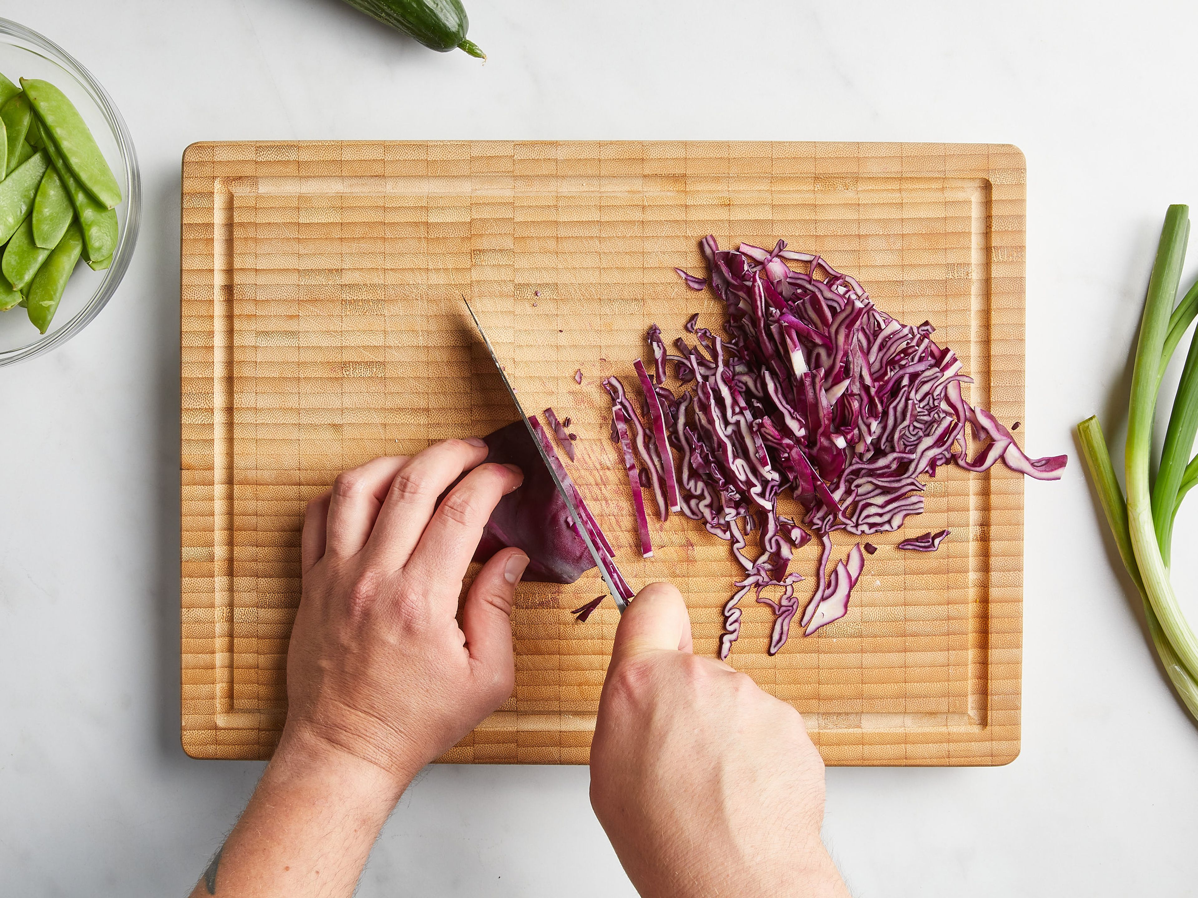 Bring a pot of water to a boil over medium-high heat. In the meantime, slice the cucumber into thin strips. Thinly slice the scallions. Chop up the red cabbage. Slice the snow peas into bite-sized pieces. Cut the stems and leaves of the cilantro. Roughly chop the peanuts.