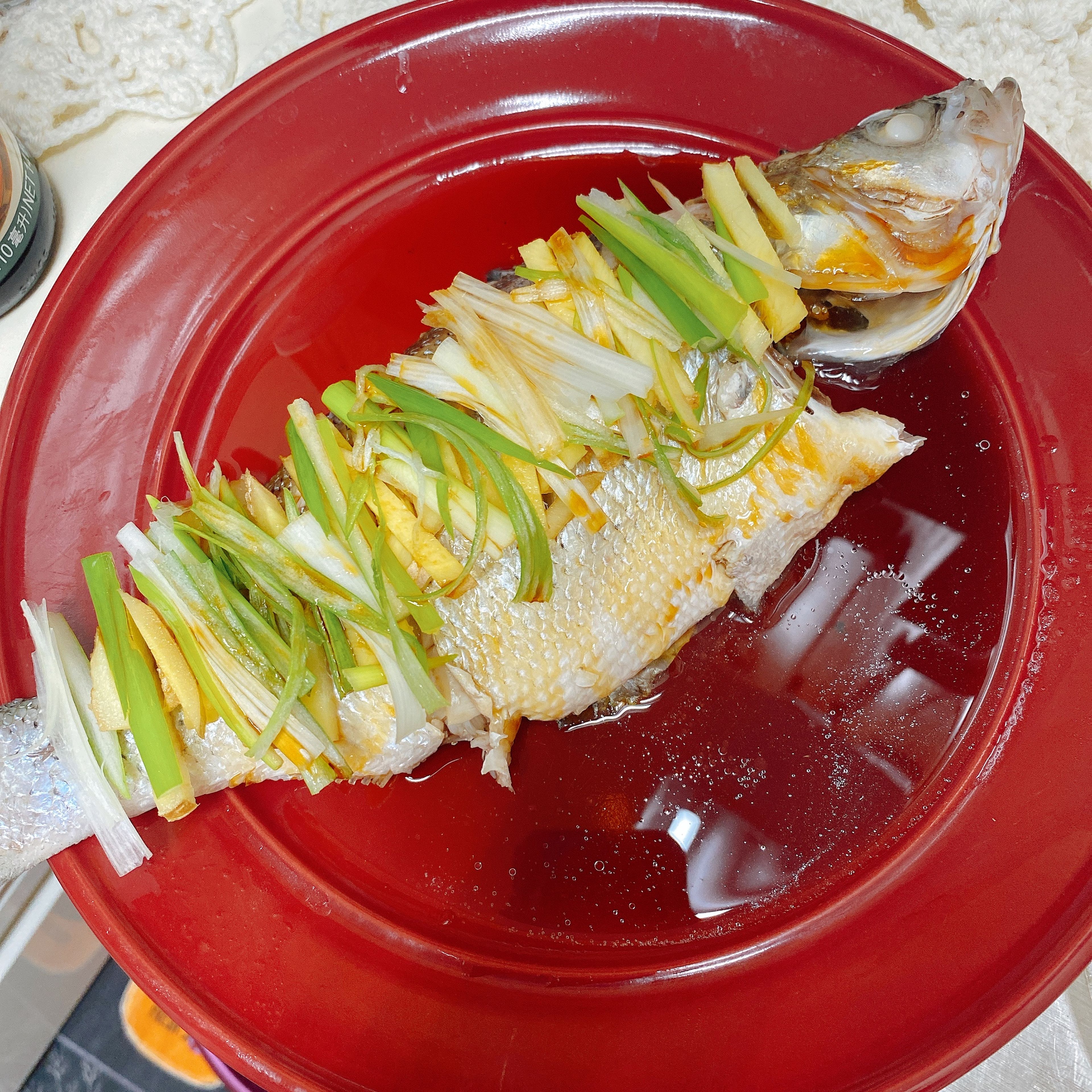 Take the plate out, DISCARD the water left on the plate (or move the fish to another plate), and take out the ginger and scallions. This is very important to get rid of the bloody taste. Lay the rest of ginger and scallions on top of the fish and add the soy sauce for seafood.
