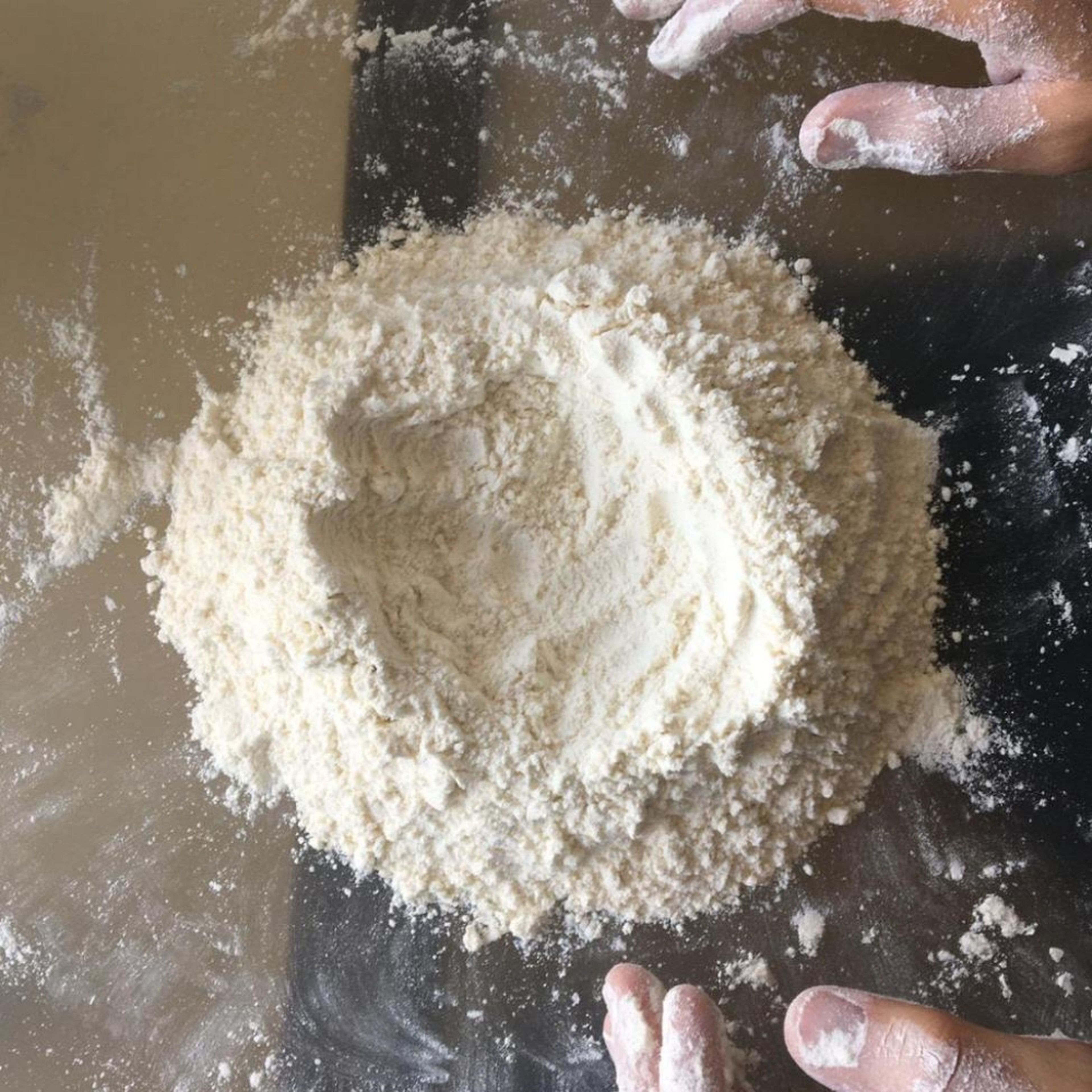 Mix flour and sugar on a flat surface and make a well in the middle.