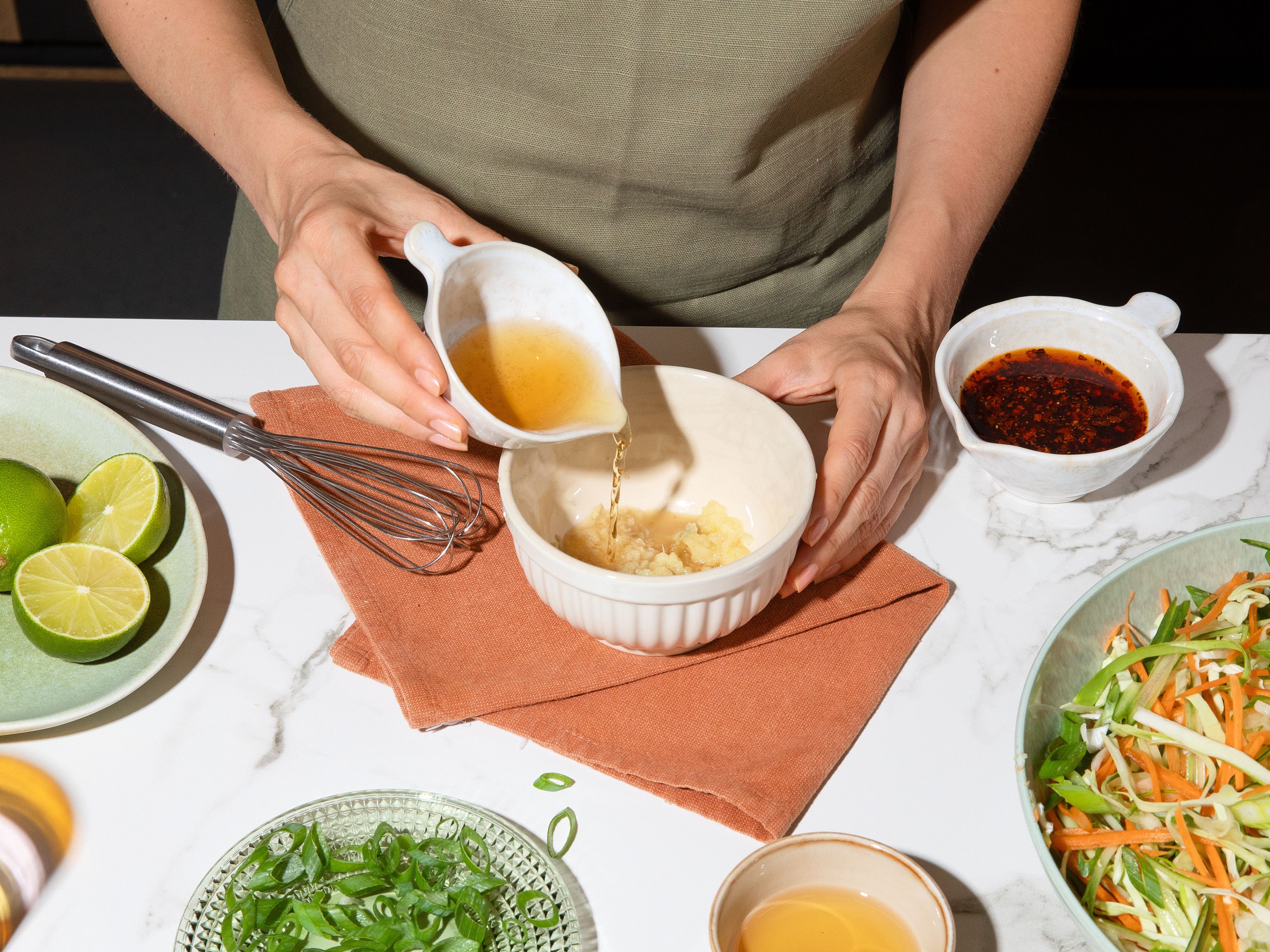 For the dressing, finely grate garlic and ginger into a small bowl. Add soy sauce, rice vinegar, agave syrup, chili oil, and sesame oil. Squeeze in lime juice and stir everything together. Add to the prepared vegetables and mix, then set aside so the salad can absorb the flavors.