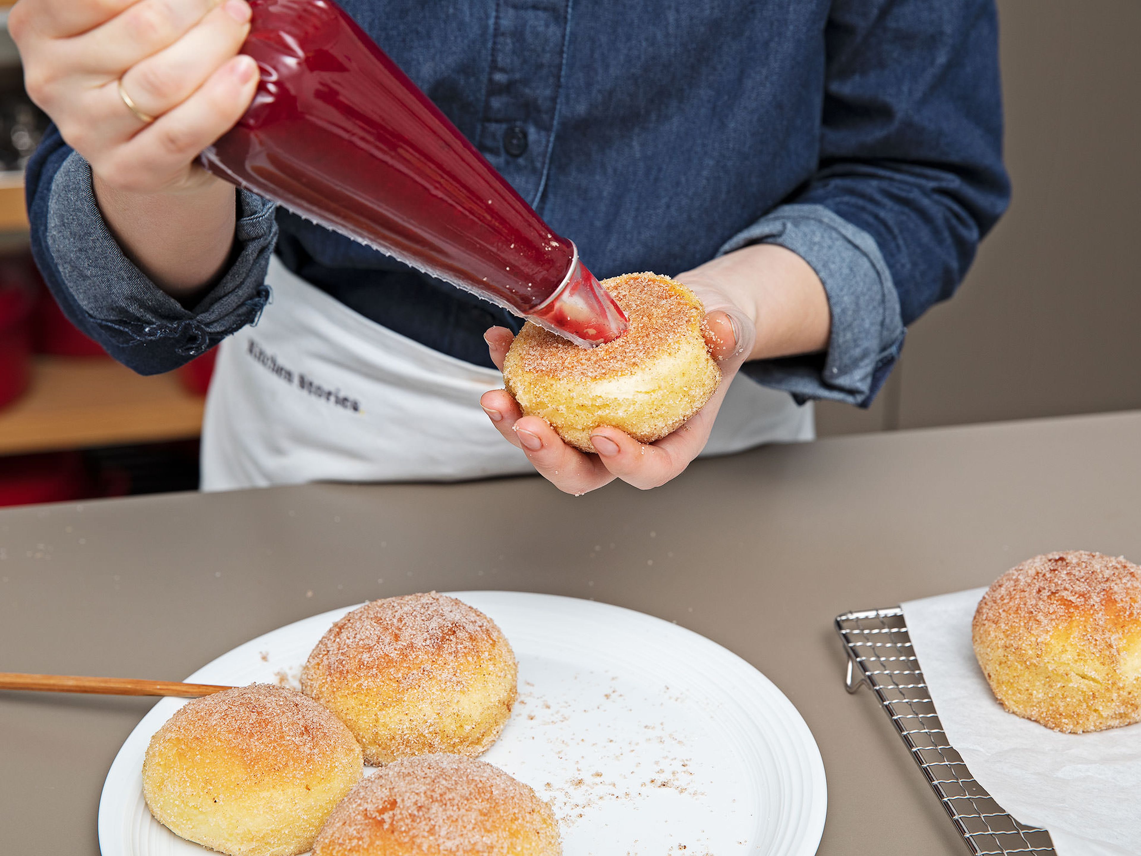 Fill a piping bag fitted with a tip with the cranberry sauce. With a small knife, cut an X into the bottom of the doughnut, halfway into the donut. Fill this cavity with jam, leaving a little dollop on the surface. Enjoy!