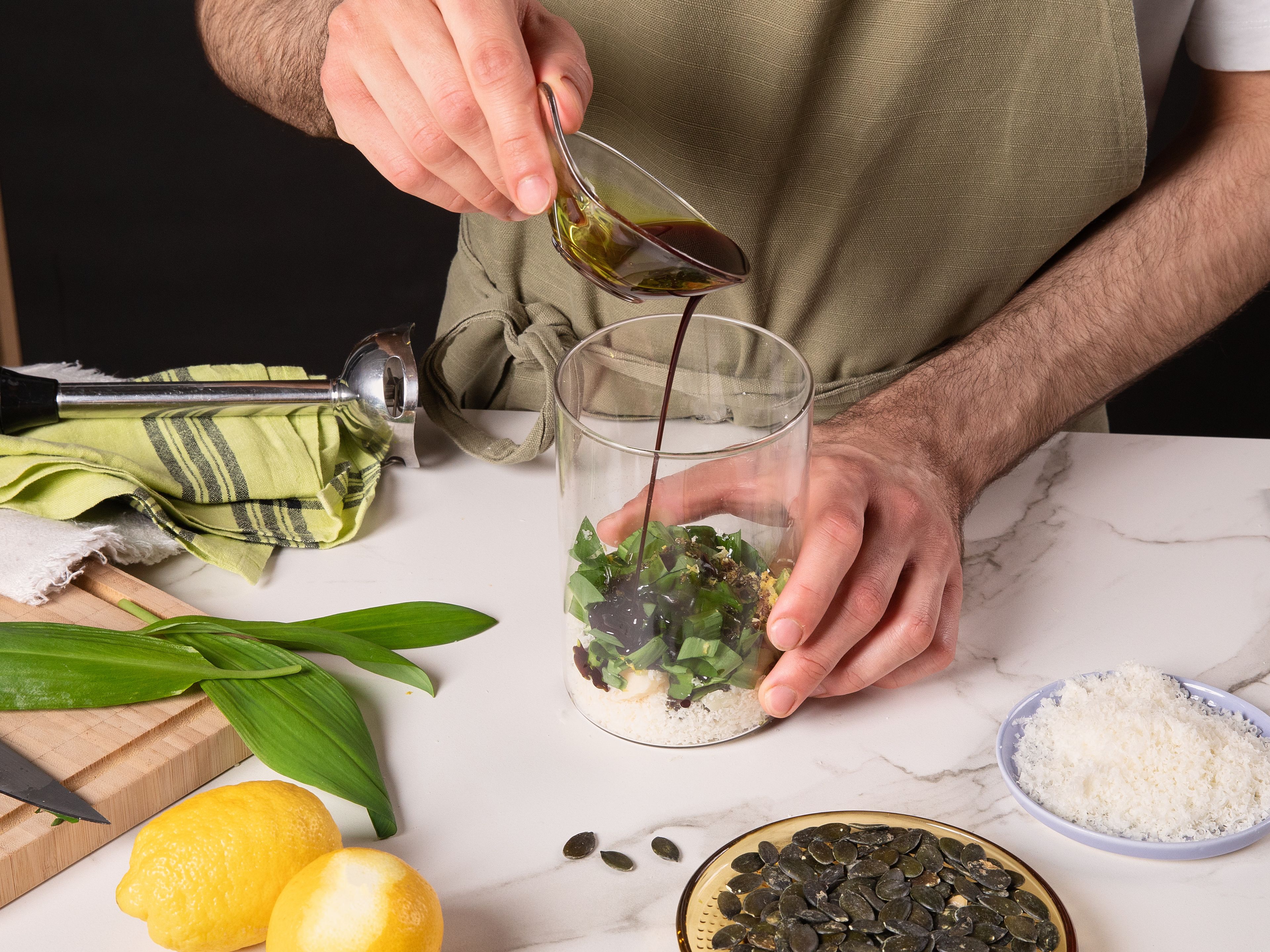 Preheat oven to 200°C/392°F (top/bottom heat). Roughly chop wild garlic, grate Parmesan, and zest lemon. In a tall container, blend wild garlic, Parmesan, lemon zest, pumpkin seeds, and pumpkin oil with an immersion blender until it becomes a pesto. Season with salt and pepper.