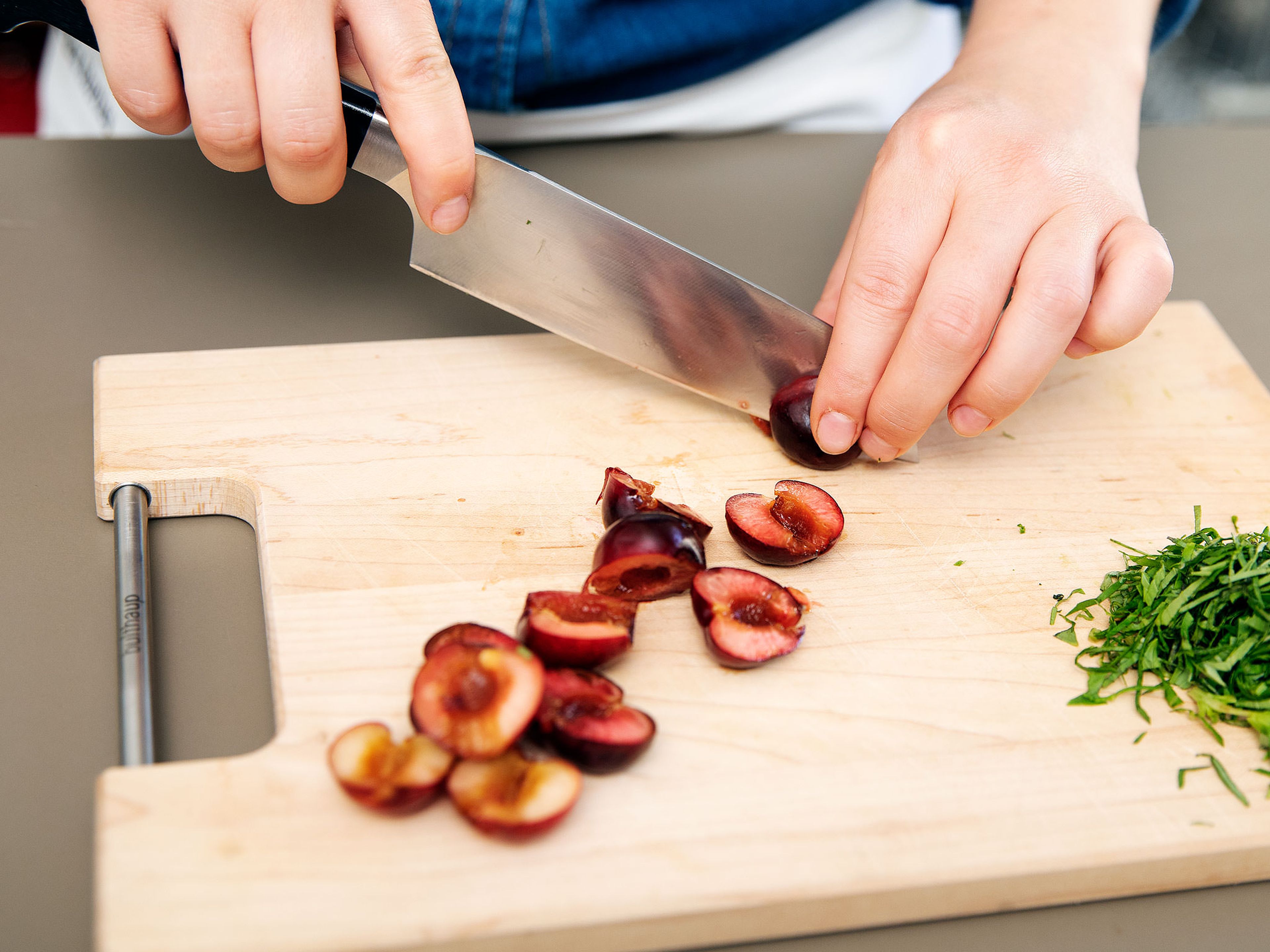 Using a knife, halve cherries and remove the pit. Pluck basil leaves from stems, thinly slice, and set aside until serving.