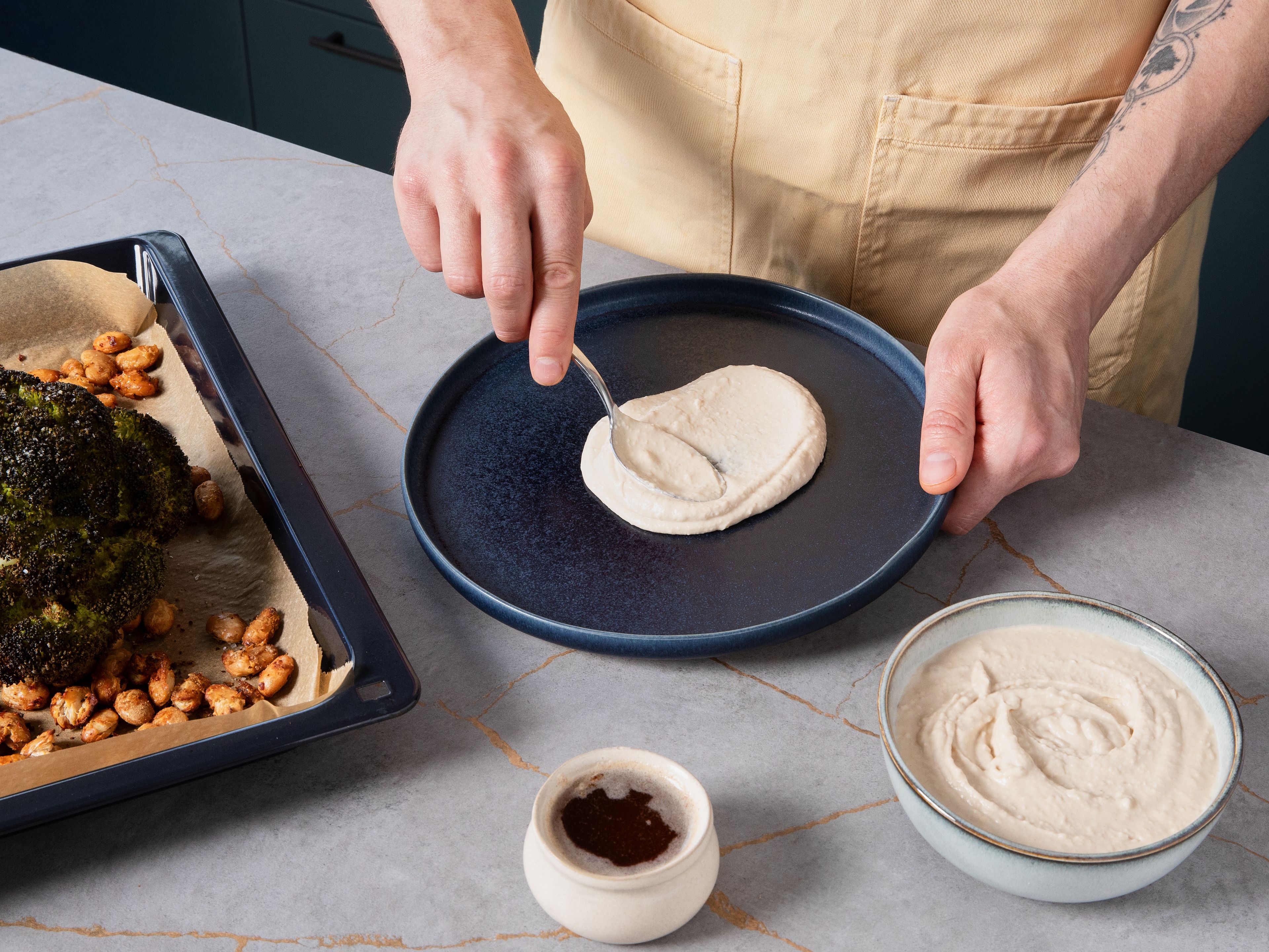 Spread hummus on a large serving plate. Place roasted broccoli on top, drizzle with warm sumac butter, and sprinkle with crispy beans. Garnish with lemon zest and toasted sesame seeds, if desired.