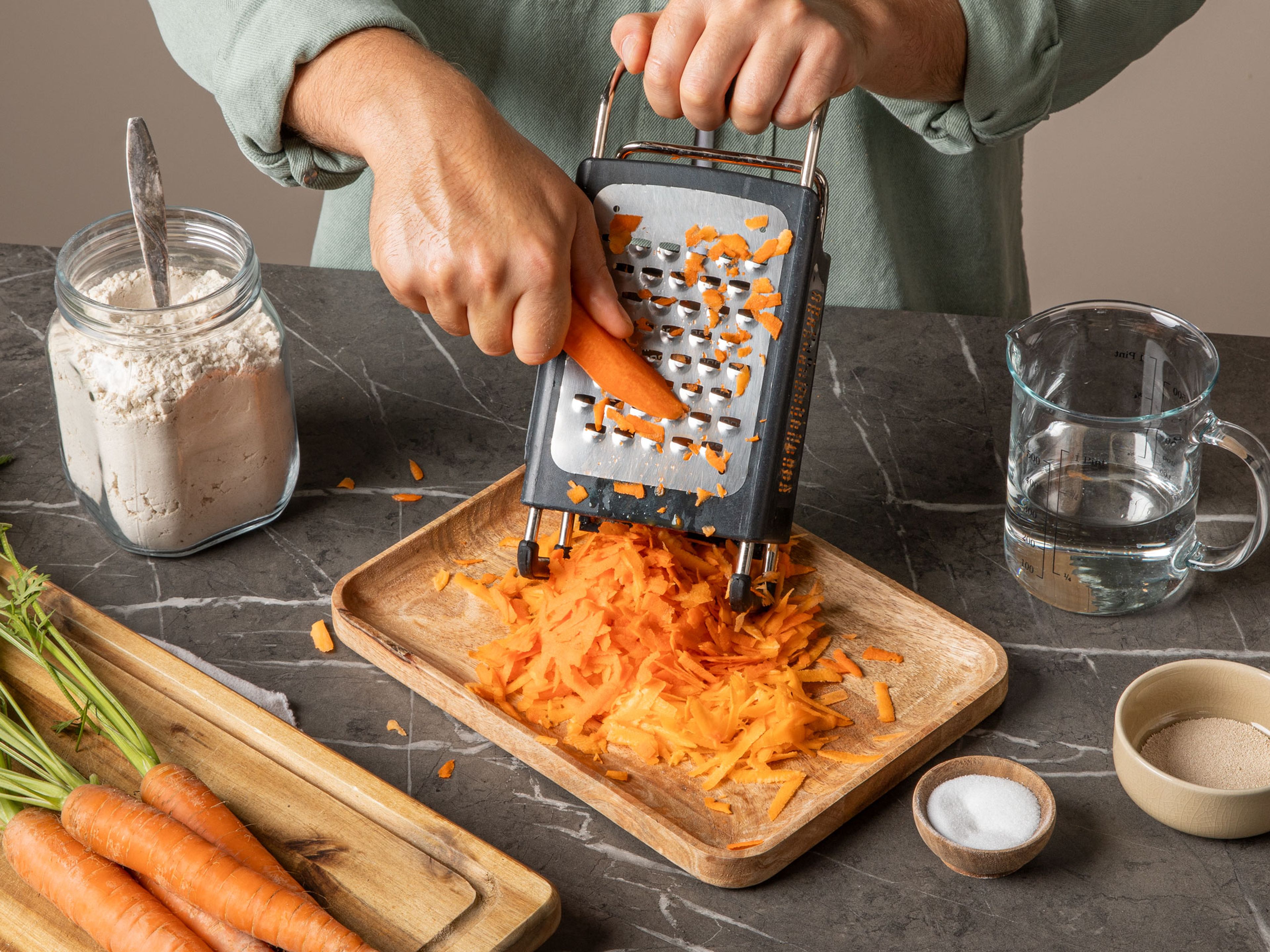 Peel and shred the carrots using a box grater and set aside. In a small bowl, whisk together yeast and sugar in the water and set aside for approx. 10 min.