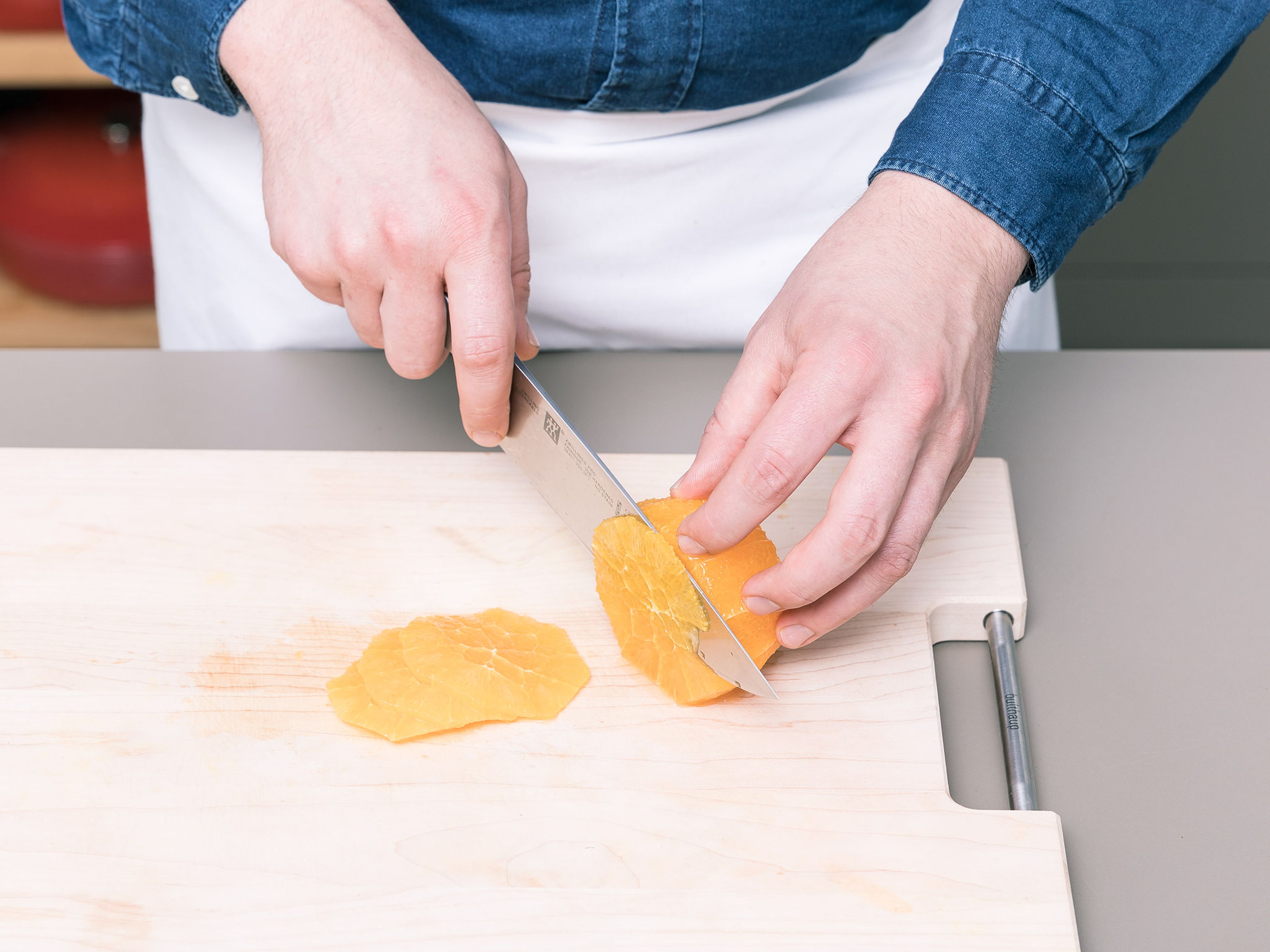 Orange schälen und in dünne Scheiben schneiden. Falls vorhanden, Kerne entfernen. Die Orangenscheiben zum Fenchel geben und vermengen.