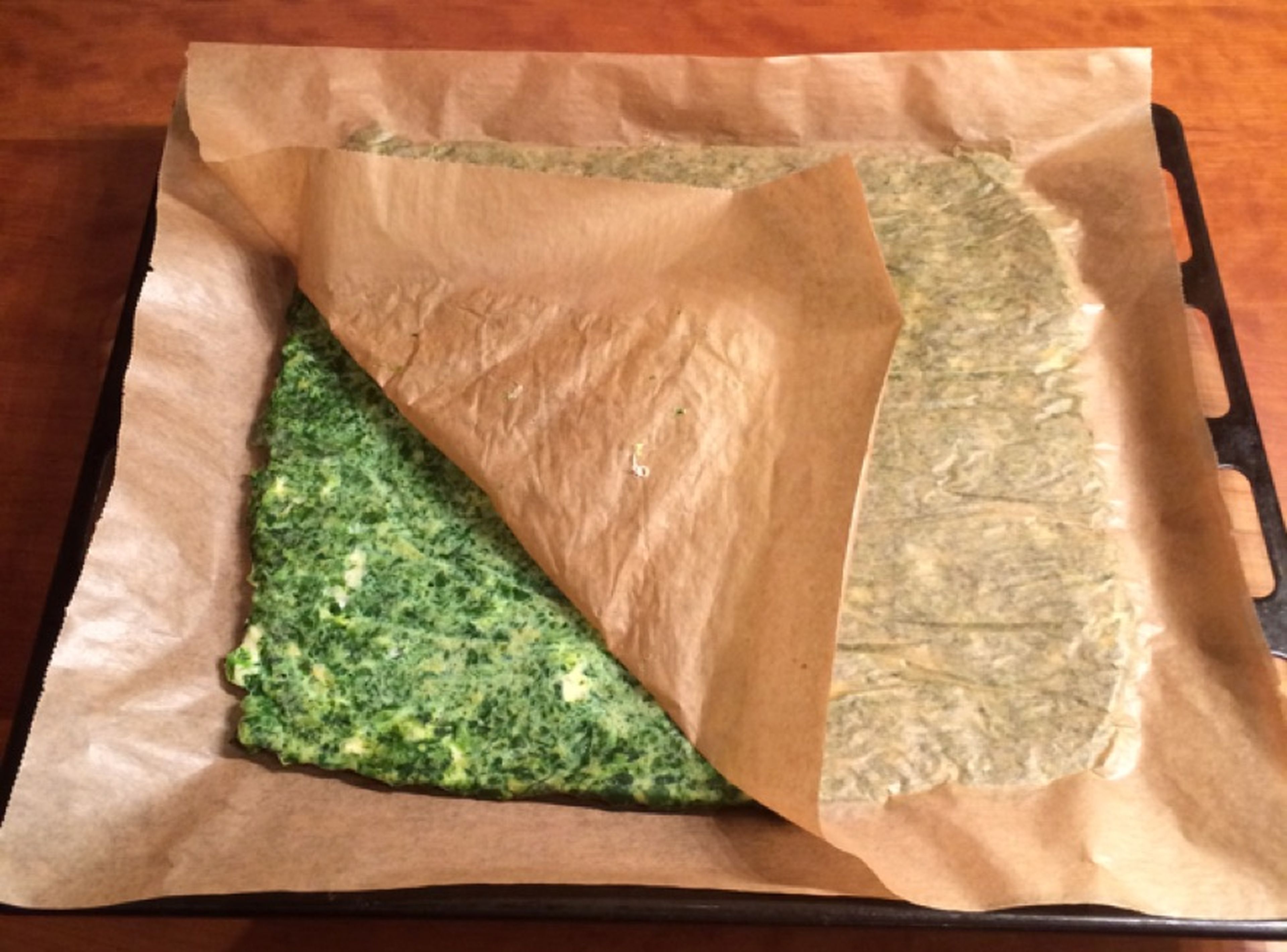Take another sheet of parchment paper to carefully turn the spinach layer upside down. Gently peel off the first sheet of parchment paper. Bake again for approx. 10 min.