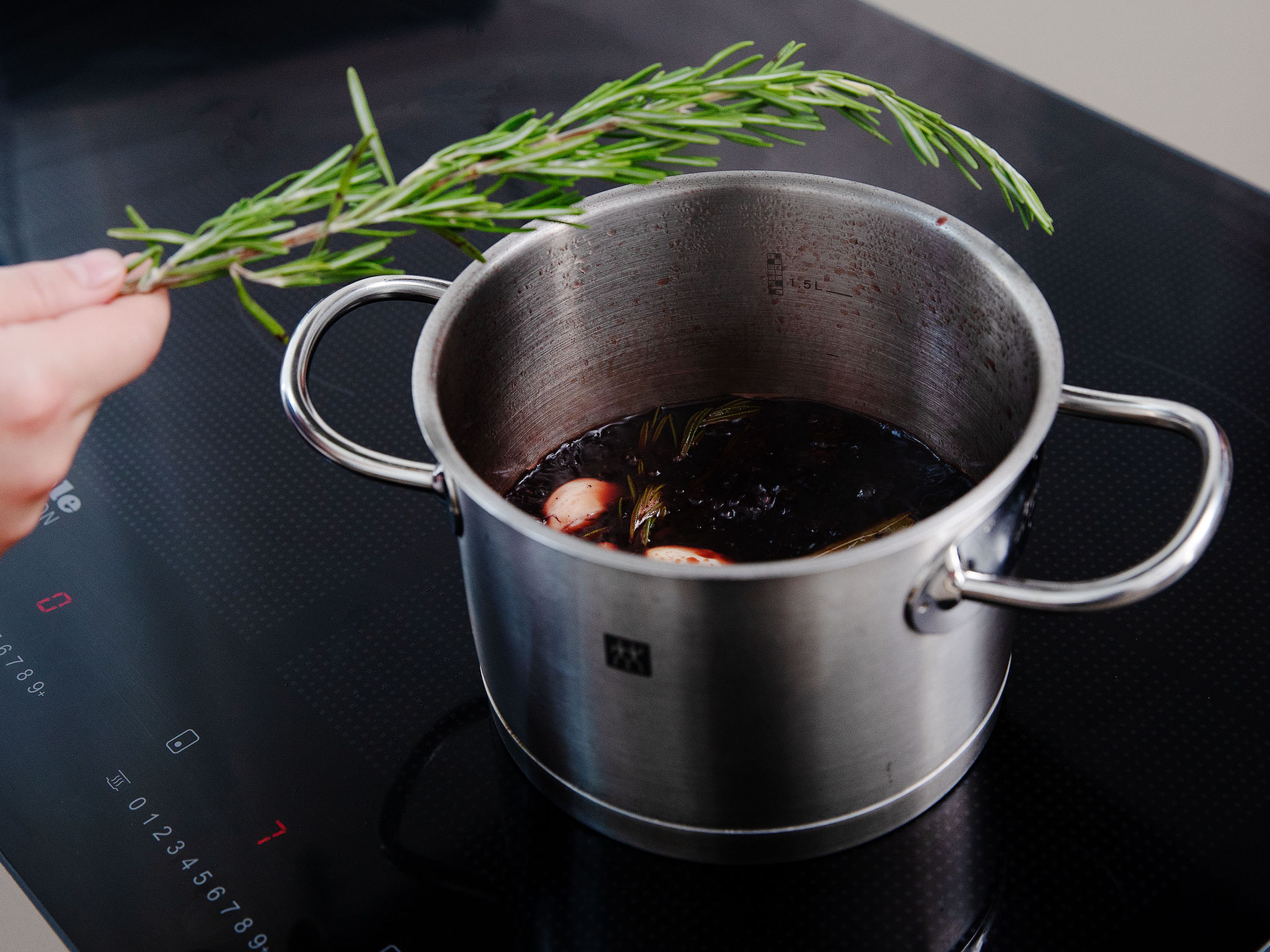Add sugar to a pot and caramelize over medium heat. Halve and juice lemon. Add cherry juice, port wine, crème de cassis, balsamic vinegar, and lemon juice. Peel and crush garlic and add to the pot together with the bay leaf and whole rosemary sprigs. Allow the sauce to reduce over medium-low heat.