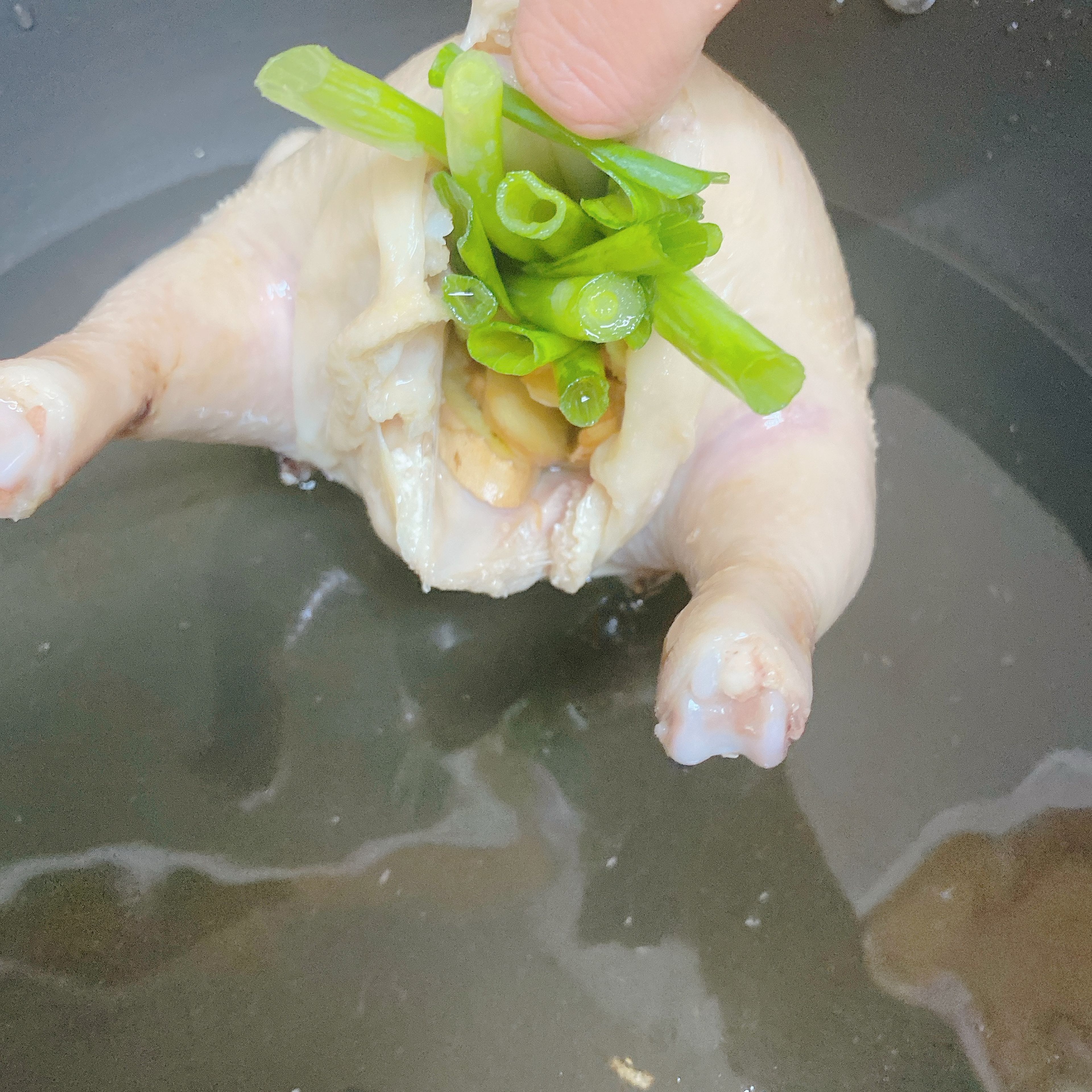 Blanch the chicken to get rid of the blood. You can add some cooking wine. While waiting, julienne the scallions and slice the ginger. Once the chicken is cleaned, give it a short message with the salt-just a little bit is enough. Then... emmm... stuff the chicken with as much ginger and scallion as possible as the picture shows.