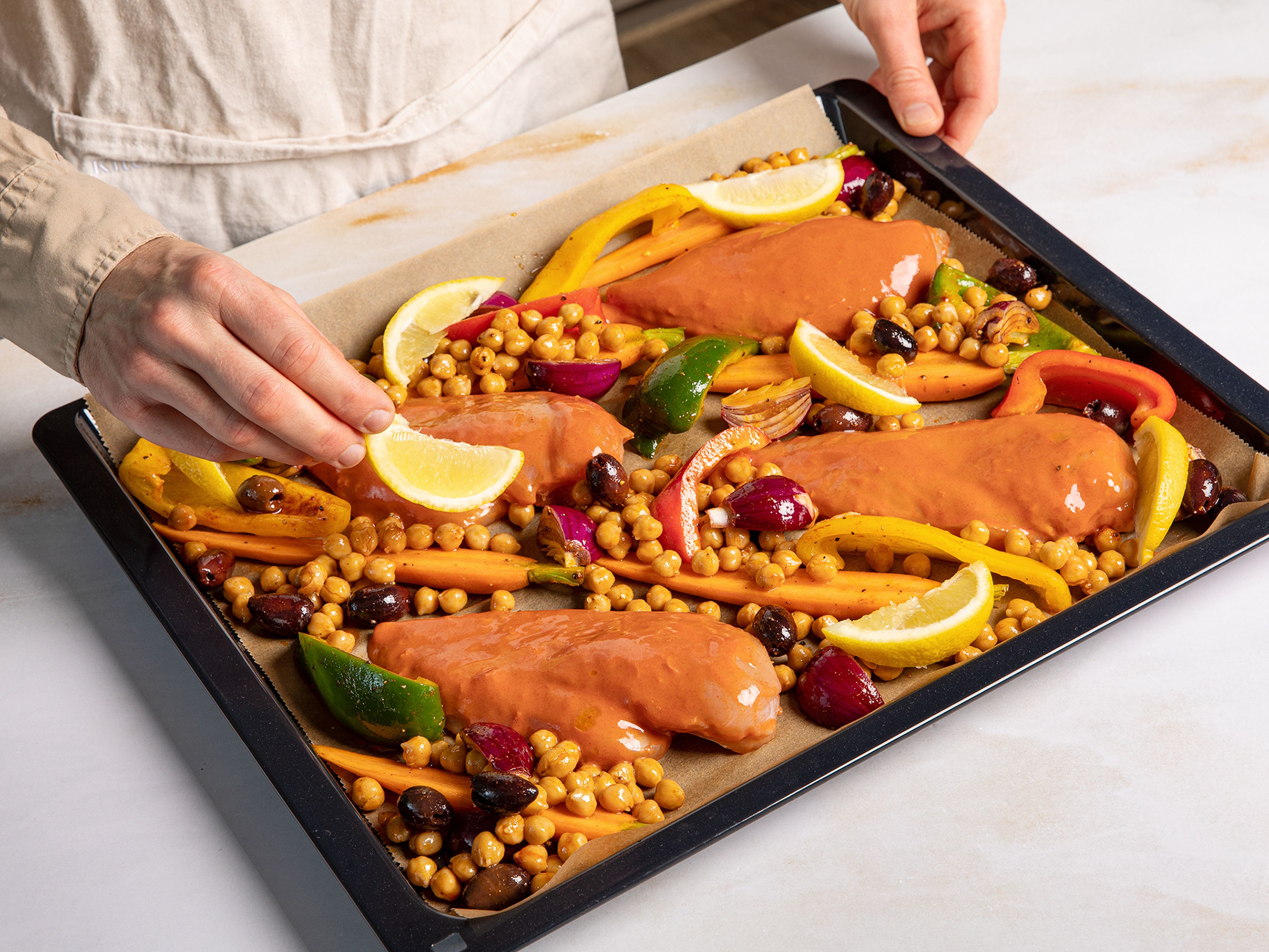 Put the vegetables and chickpeas on a baking sheet lined with baking paper and mix with olive oil, paprika, salt, and pepper. Place the chicken breasts in between, and bake for approx. 30-35 min.