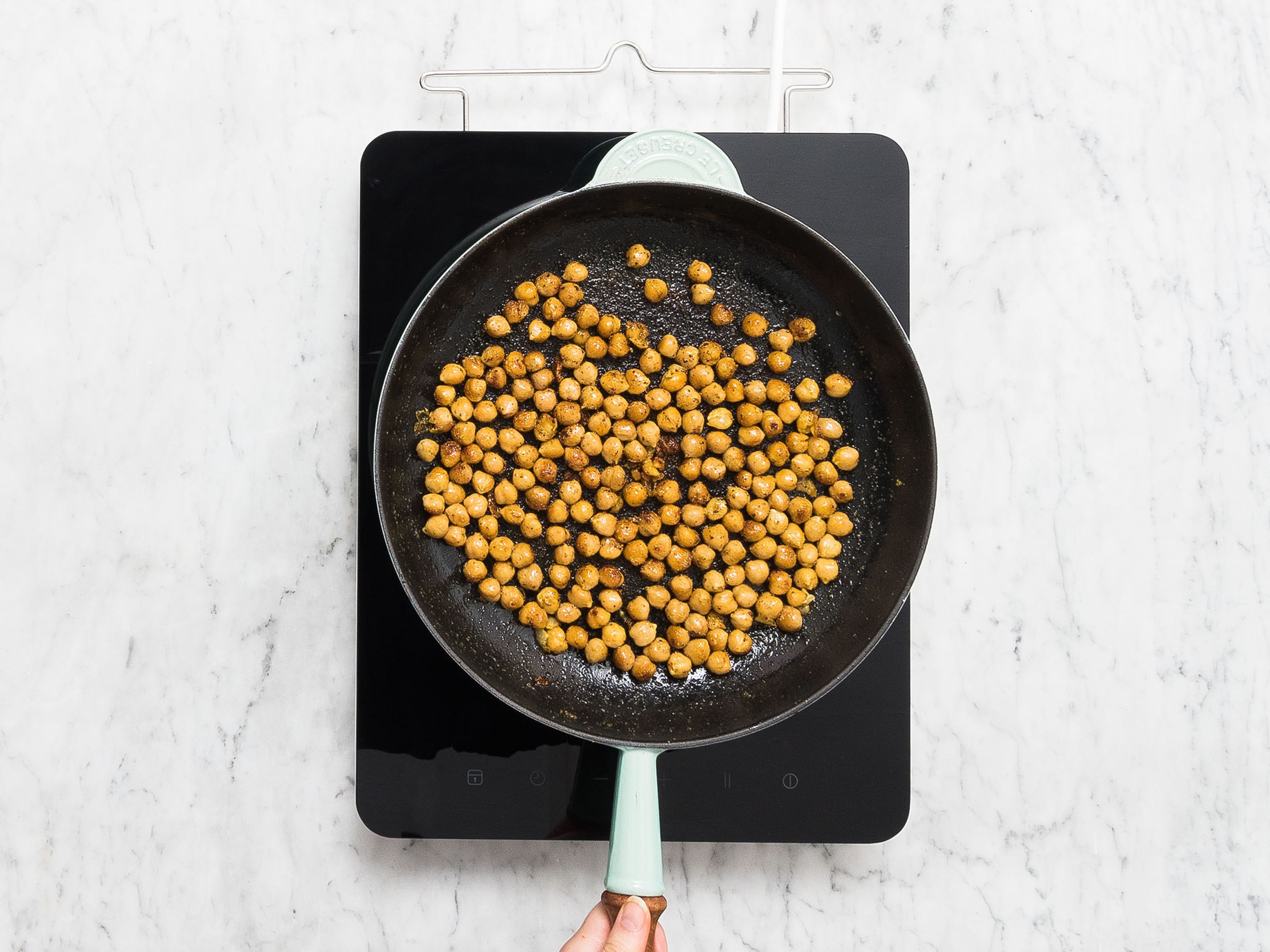 Rinse chickpeas until water runs clear, then pat dry. In a large bowl, mix chickpeas, curry powder, olive oil, and garlic powder together and season with salt and pepper. Heat a frying pan over medium-high heat and fry chickpeas for approx. 5 min., or until golden brown. Remove from pan and set aside.