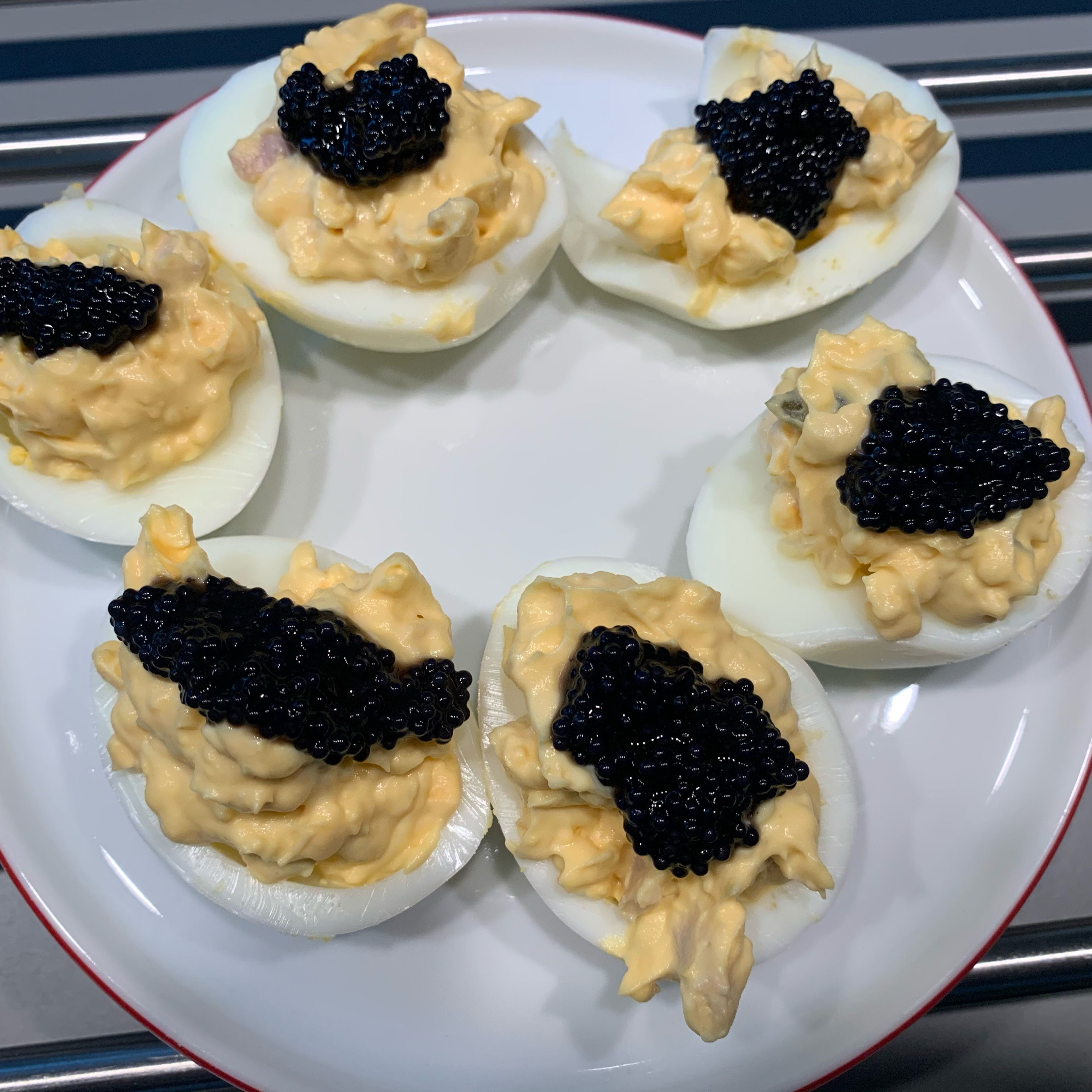 Jeweils eine Messerspitze des falschen Kaviars auf die halbierten Eier geben, man kann auch Seelachs aus der Dose nehmen.￼