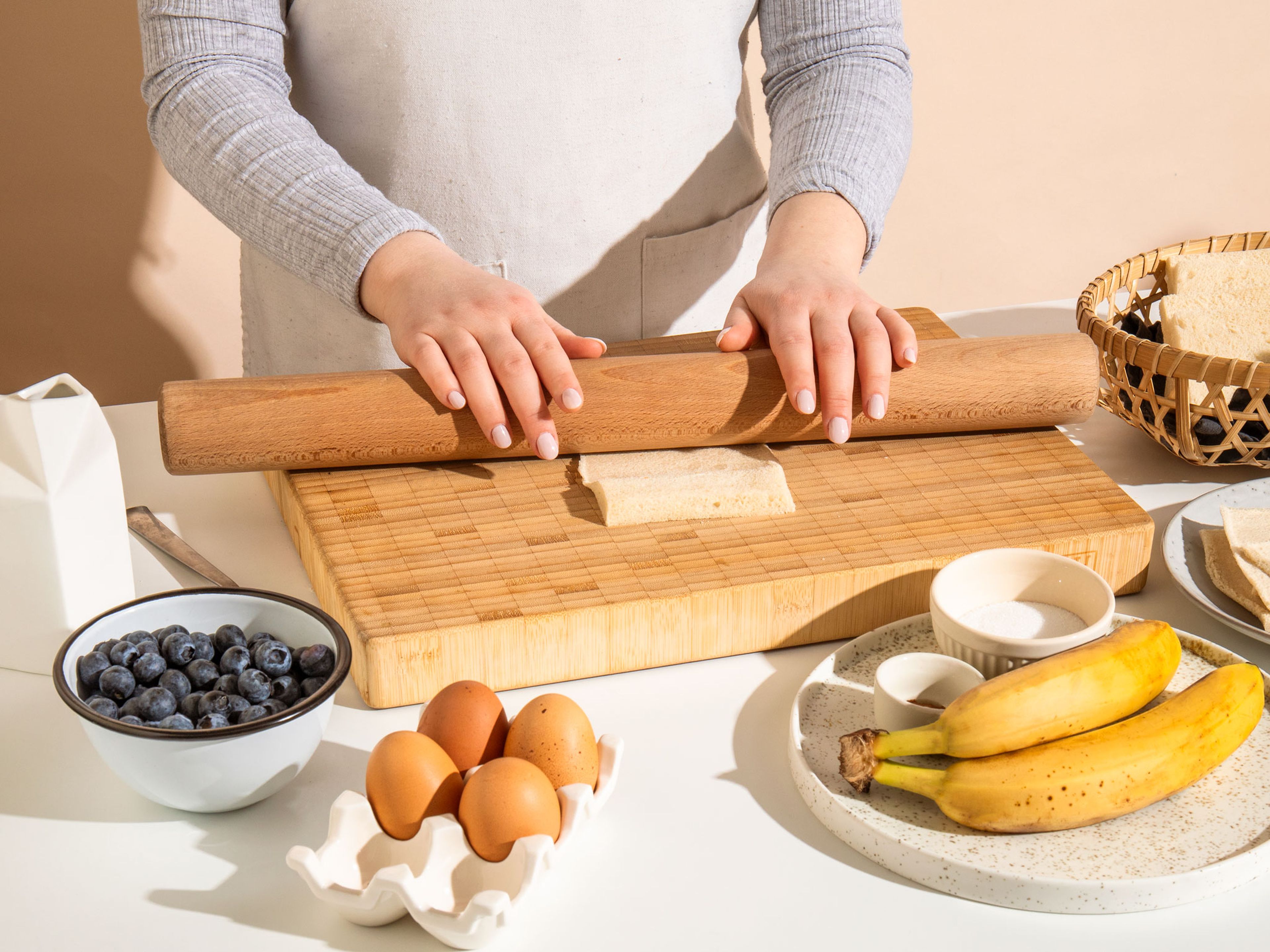 Die Ränder der Toastscheiben abschneiden und jede Scheibe mit einem Nudelholz flach ausrollen. In einer flachen Schüssel Eier mit der Milch verquirlen. Die Bananen schälen und auf einem Teller mit einer Gabel zerdrücken.