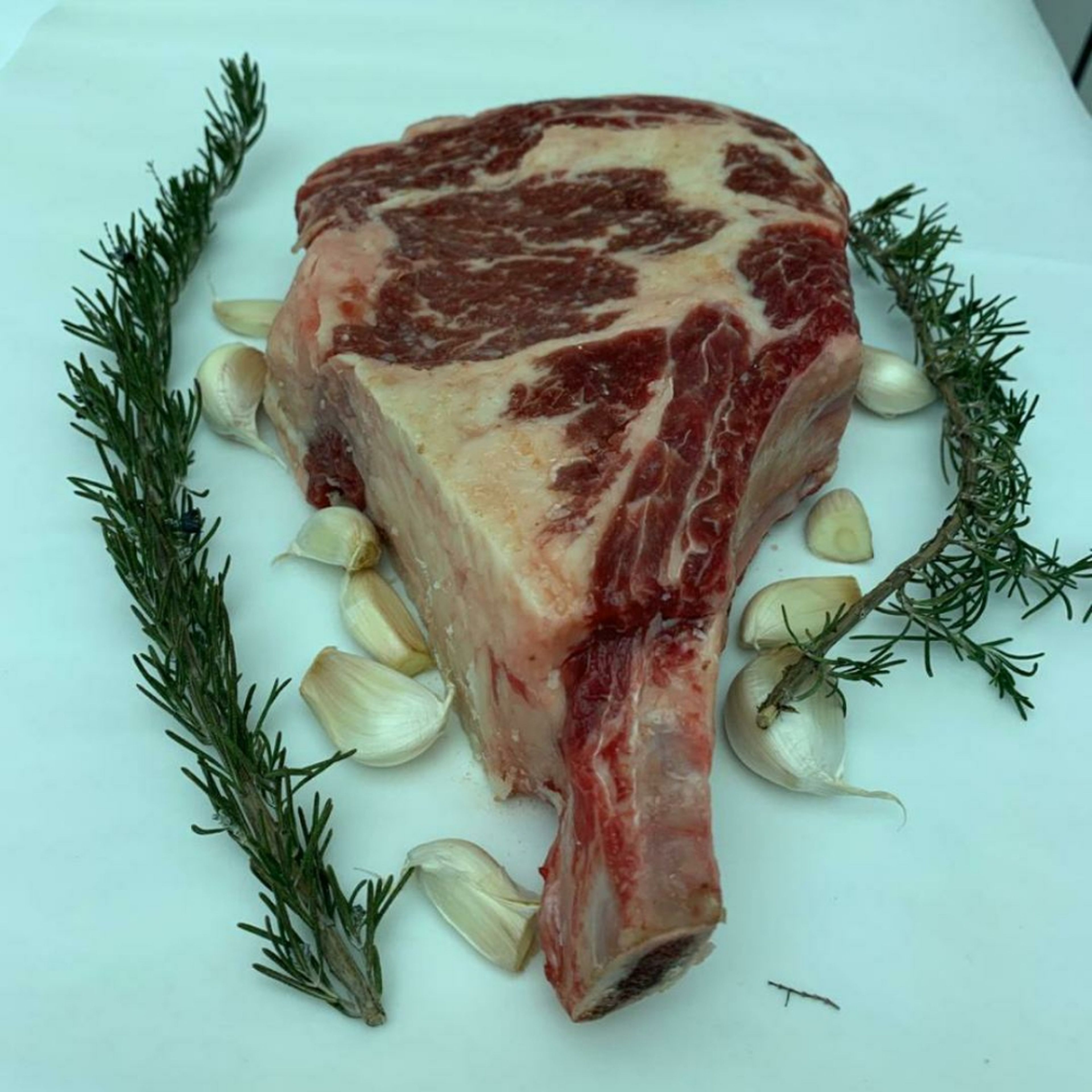 keep steak at room temperature for 1 hour sprinkle generously with salt. Then place the steak in a large baking sheet together with garlic cloves and rosemary branches (if not available use dried rosemary)