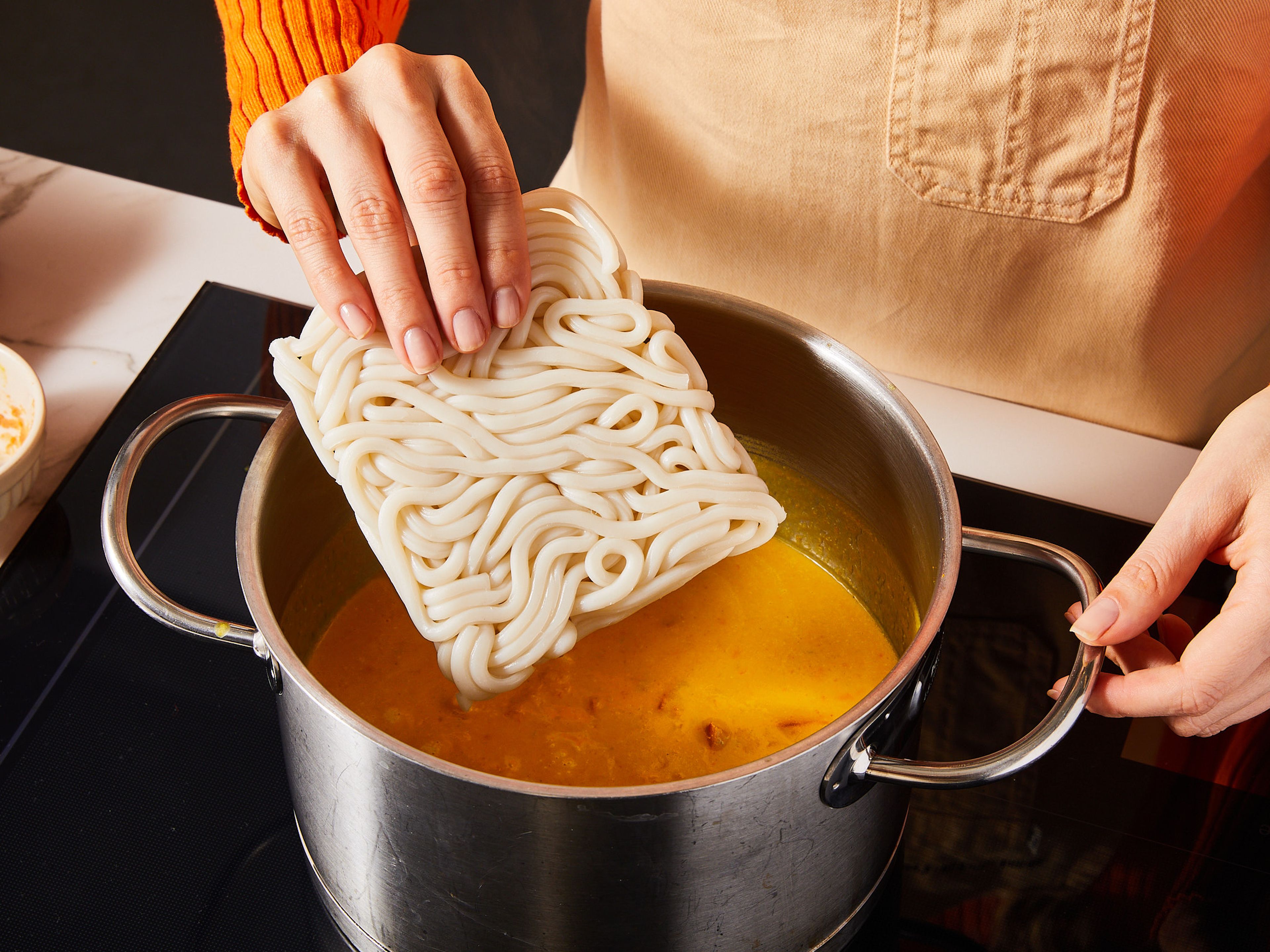 Mit einem Stabmixer kurz anpürieren, so dass die Soße cremig wird, aber noch einige Kürbiswürfel übrig bleiben. Misopaste hinzufügen und rühren, bis sie sich aufgelöst hat. Nun die Udon-Nudeln hinzugeben und ca. 3 Min. erhitzen während du sie vorsichtig auseinanderziehst.