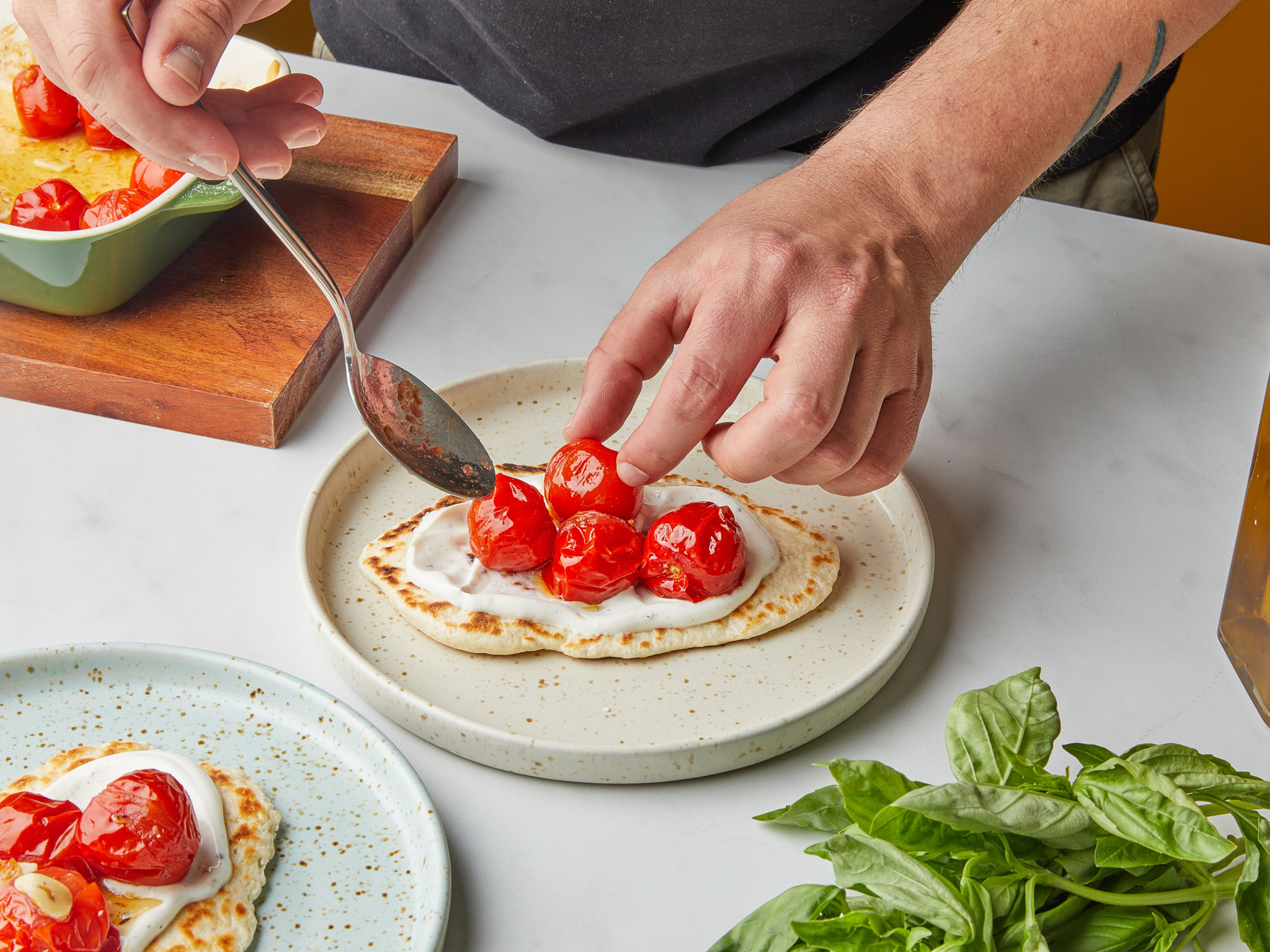 Season the remaining yogurt with salt and pepper, then spread the yogurt over the flatbreads. Next, put the cherry tomatoes and fresh basil leaves on the breads, and sprinkle with sea salt. Serve immediately and enjoy!