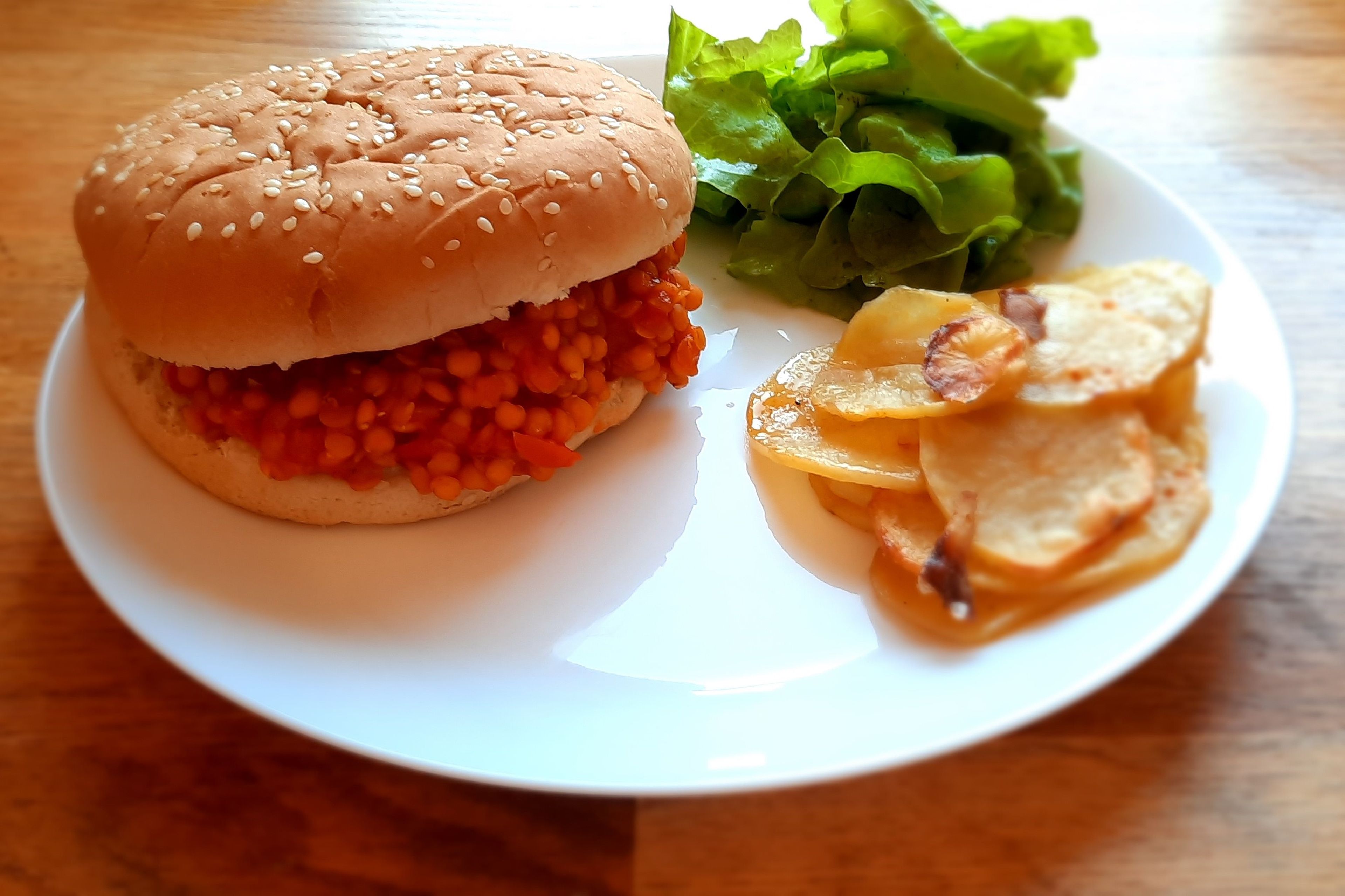 Die Linsen auf zwischen den Burgerbrötchen anrichten und mit den Kartoffelchips und einem grünen Salat servieren.