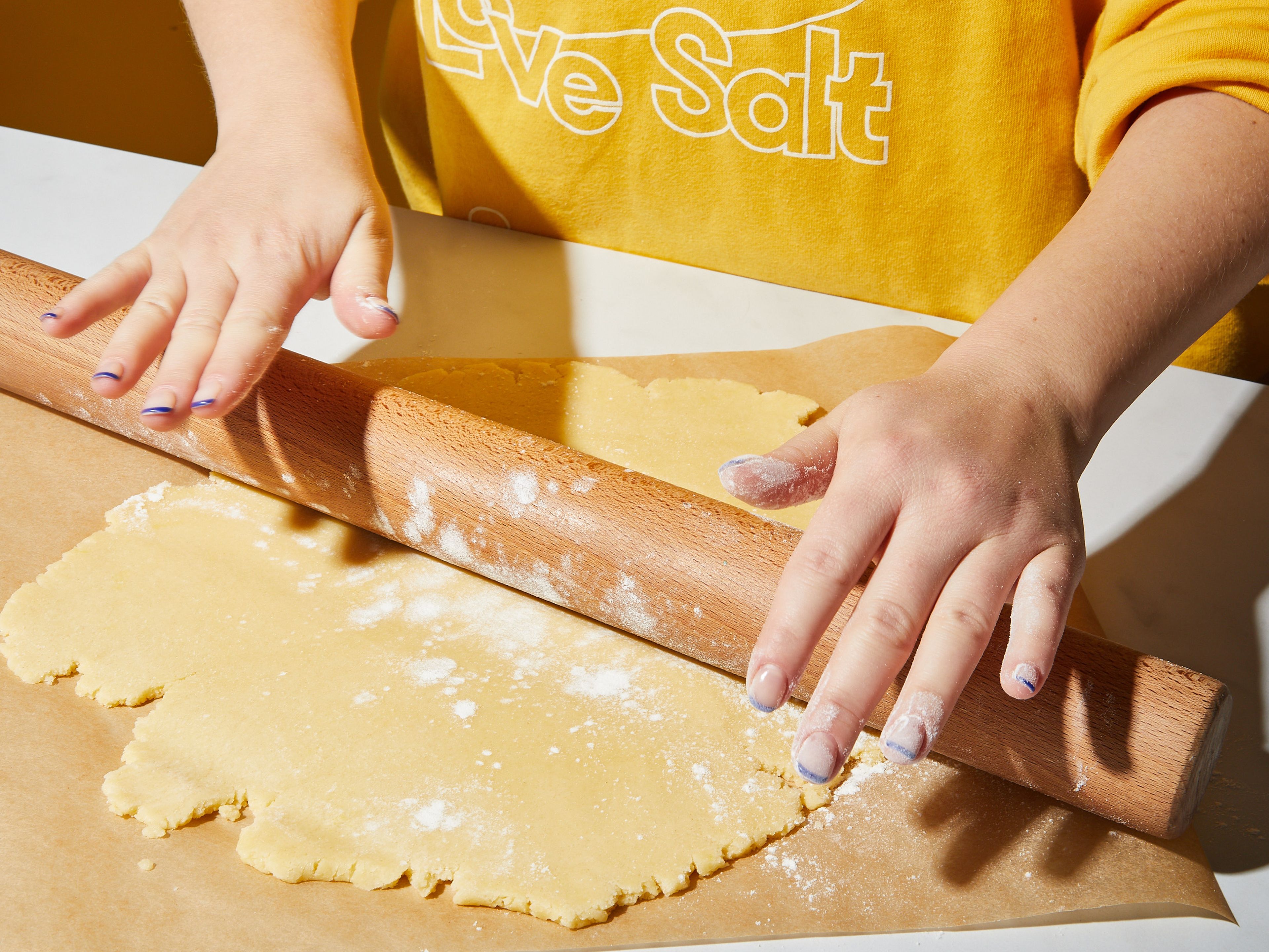 Den Ofen auf 180°C vorheizen. Den Teig in zwei Hälften teilen und jede Hälfte zwischen zwei Blättern Backpapier dünn ausrollen.