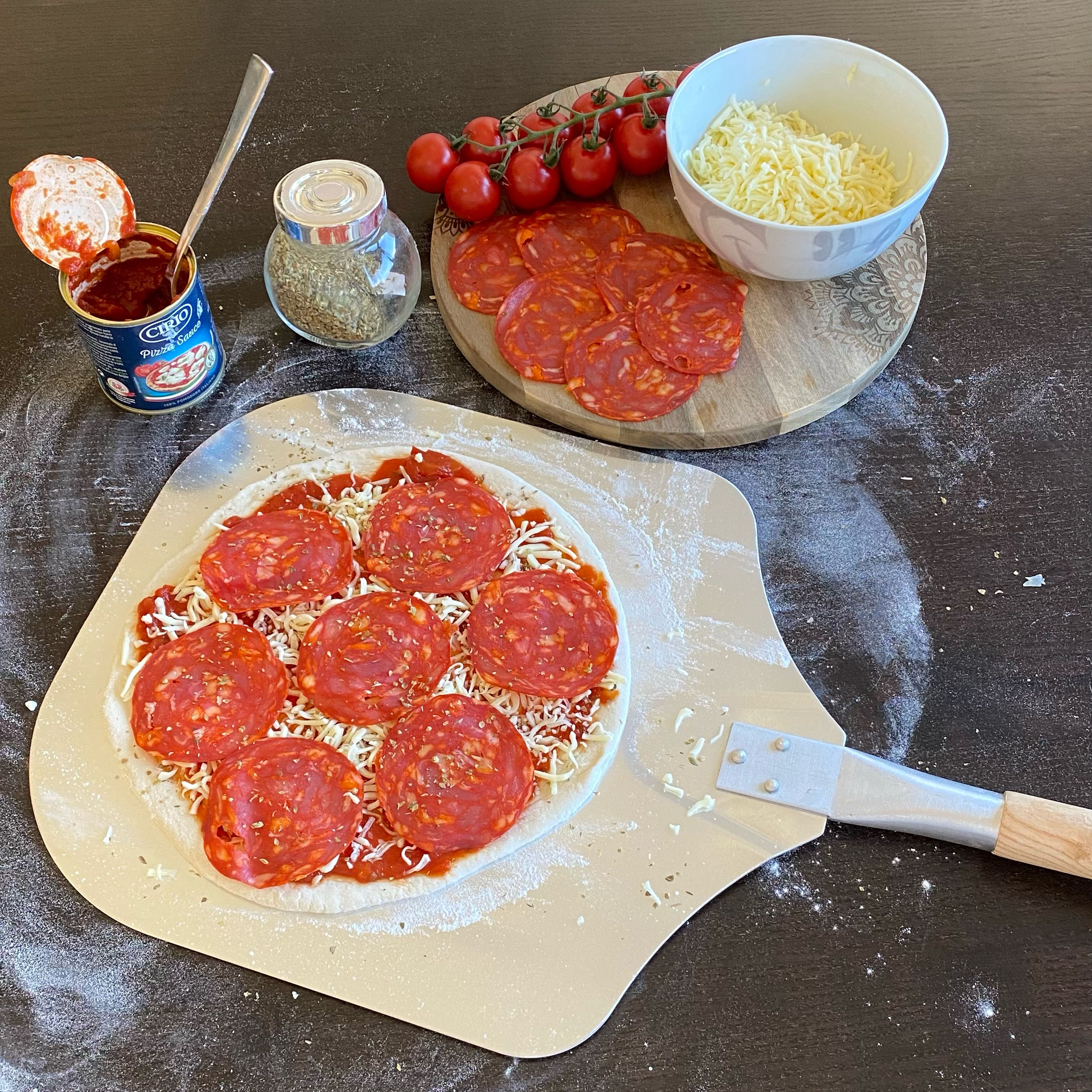 Tipp: Die Pizza bereits vor dem Belegen auf die Pizzaschaufel legen um sie später einfacher in den Ofen zu bekommen! 

Pro Pizza 2-3 EL (je nach Größe des Pizzabodens) Tomatensoße gleichmäßig auf dem Pizzaboden verteilen, mit Basilikum und 1/3 Beutel Pizzakäse bestreuen und mit Salami belegen.