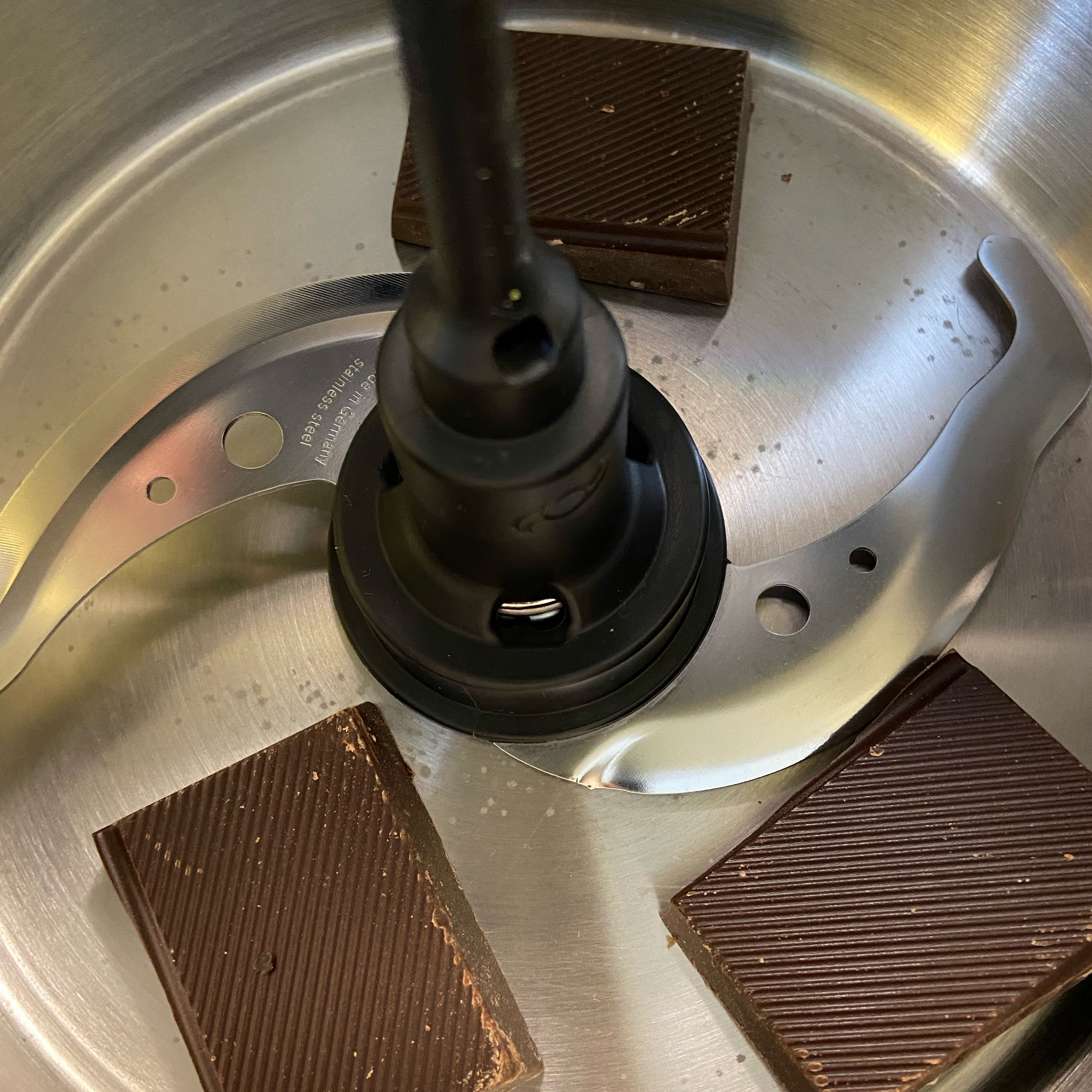 Universalmesser in den Cookit einsetzten. Die Schokolade im Cookit mit dem Universalmesser zerkleinern (Universalmesser | Stufe 18 | 10 Sek.). Nicht zu fein. Die Schokoladenstücke in eine extra Schüssel geben und zur Seite stellen.