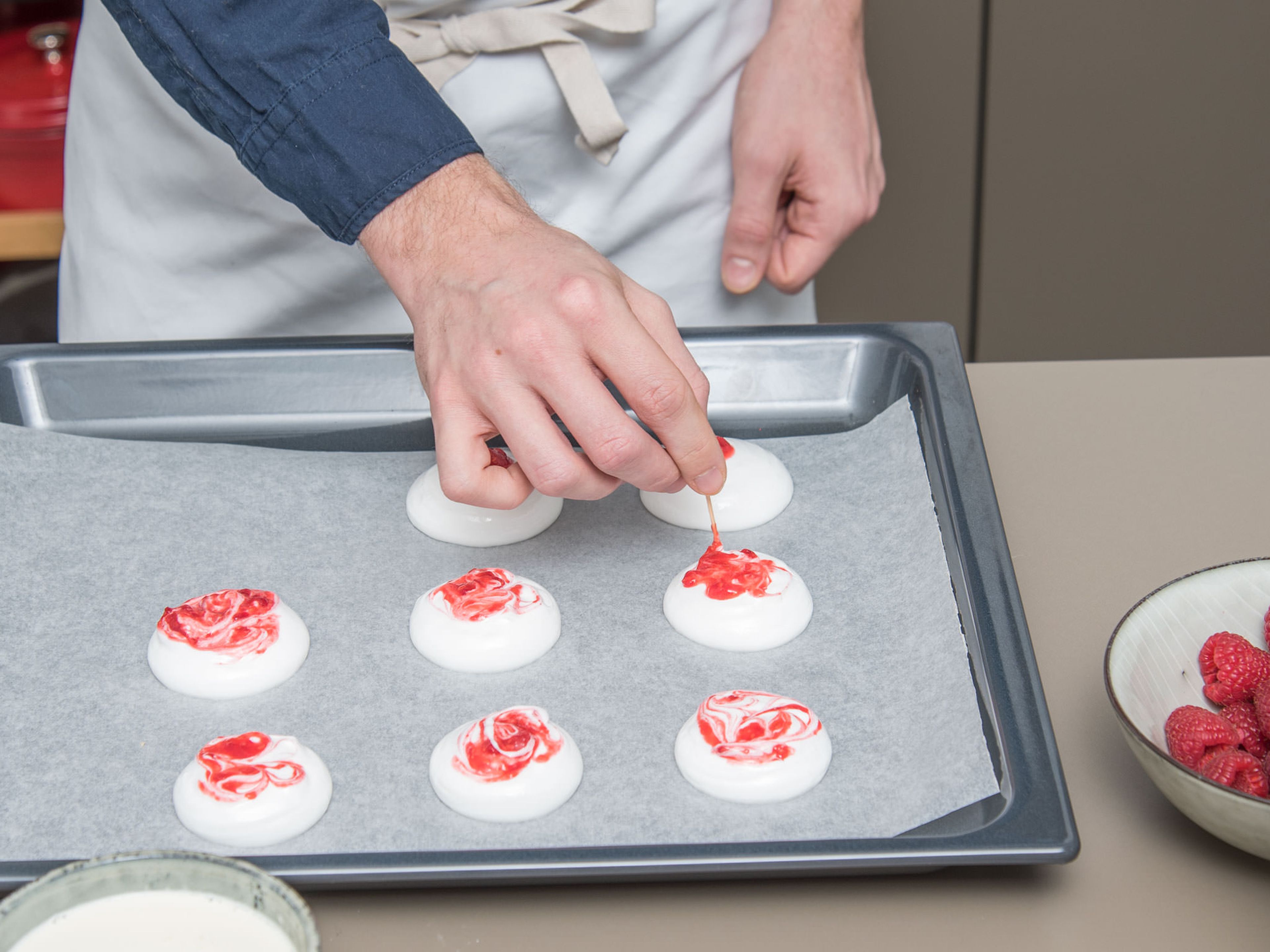 Add meringue to a piping bag. Pipe 5-cm/2 in. wide circles onto a parchment-lined baking sheet. Leave some space between. Top with some raspberry purée and swirl with a tooth pick.