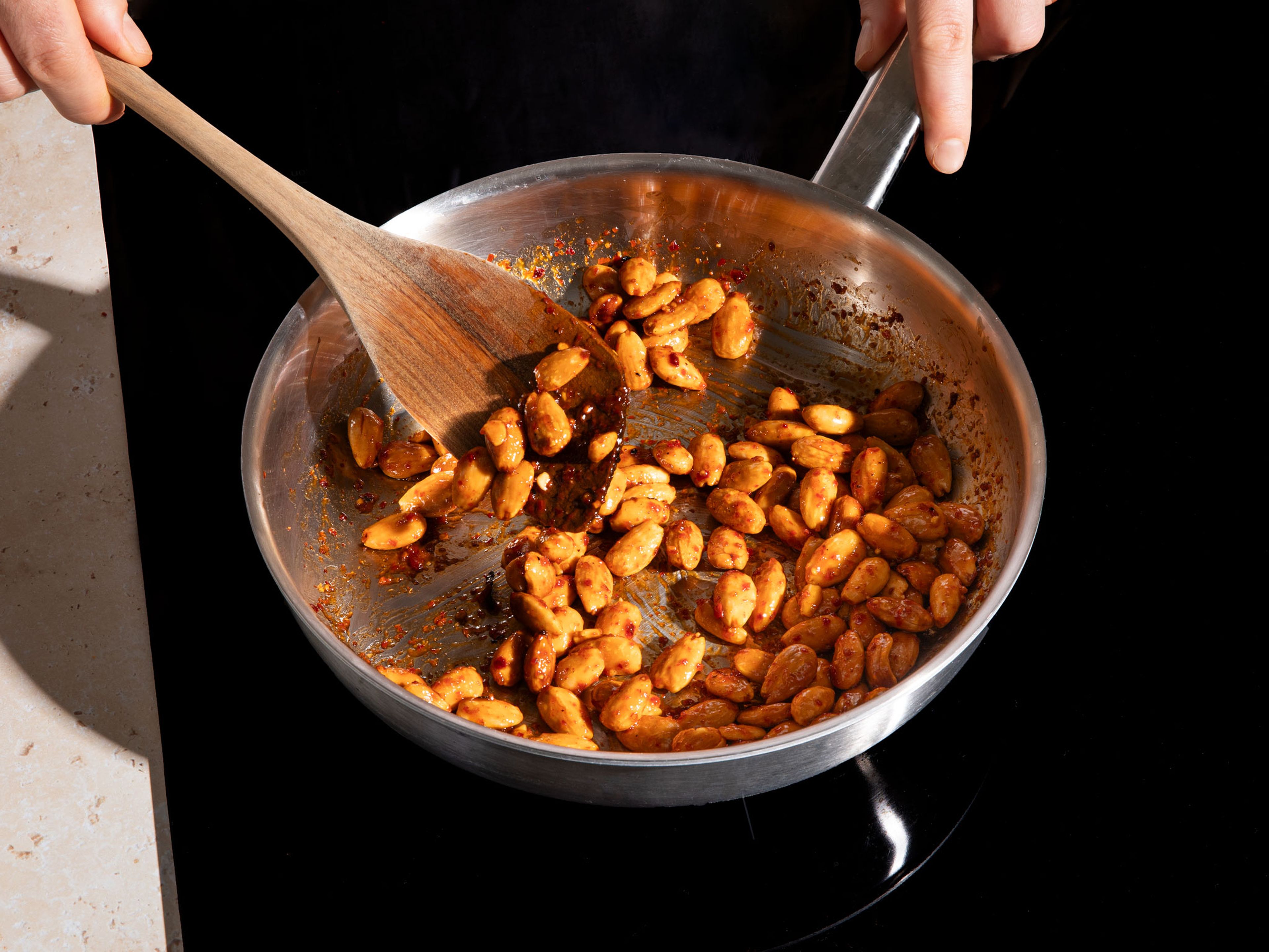 In the meantime, prepare the harissa nuts. Prepare a baking sheet with parchment paper. Mix the maple syrup, harissa and water. Place the nuts in a pan and pour the harissa mixture over them. Stir over a medium heat for approx. 5–10 min. Then transfer to the prepared baking sheet and leave to cool.