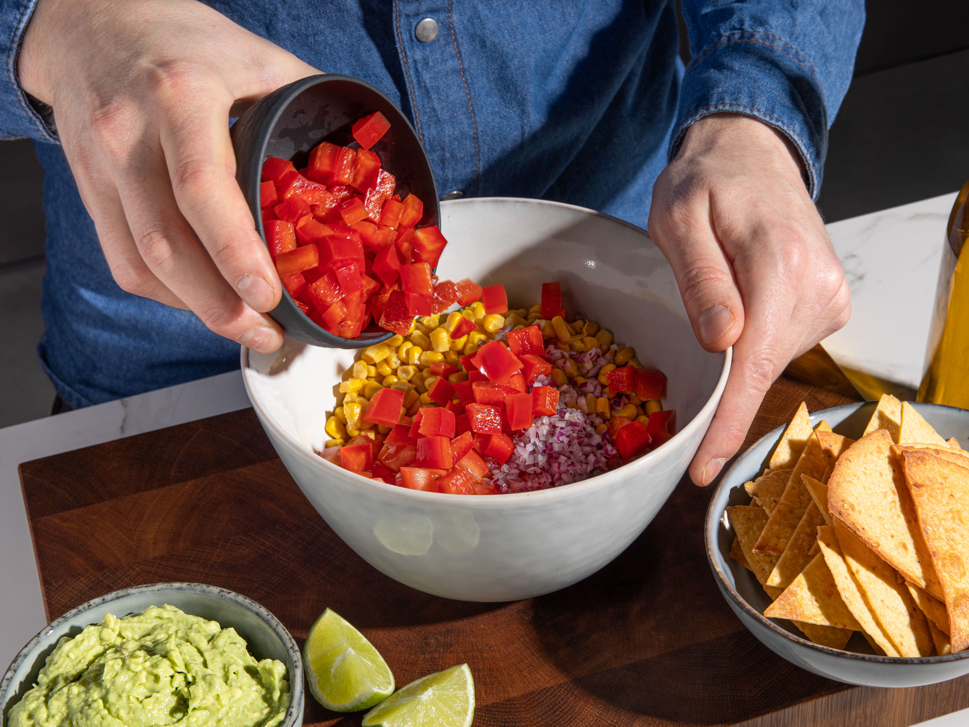 Make a quick guacamole by mashing the avocado with some lime juice to taste, then season with salt and pepper. Set aside. Drain corn, then dice tomato and deseeded red bell pepper. In a small bowl, mix together corn, tomatoes, bell pepper, and remaining red onion. Season to taste with olive oil, lime juice, salt, and pepper.
