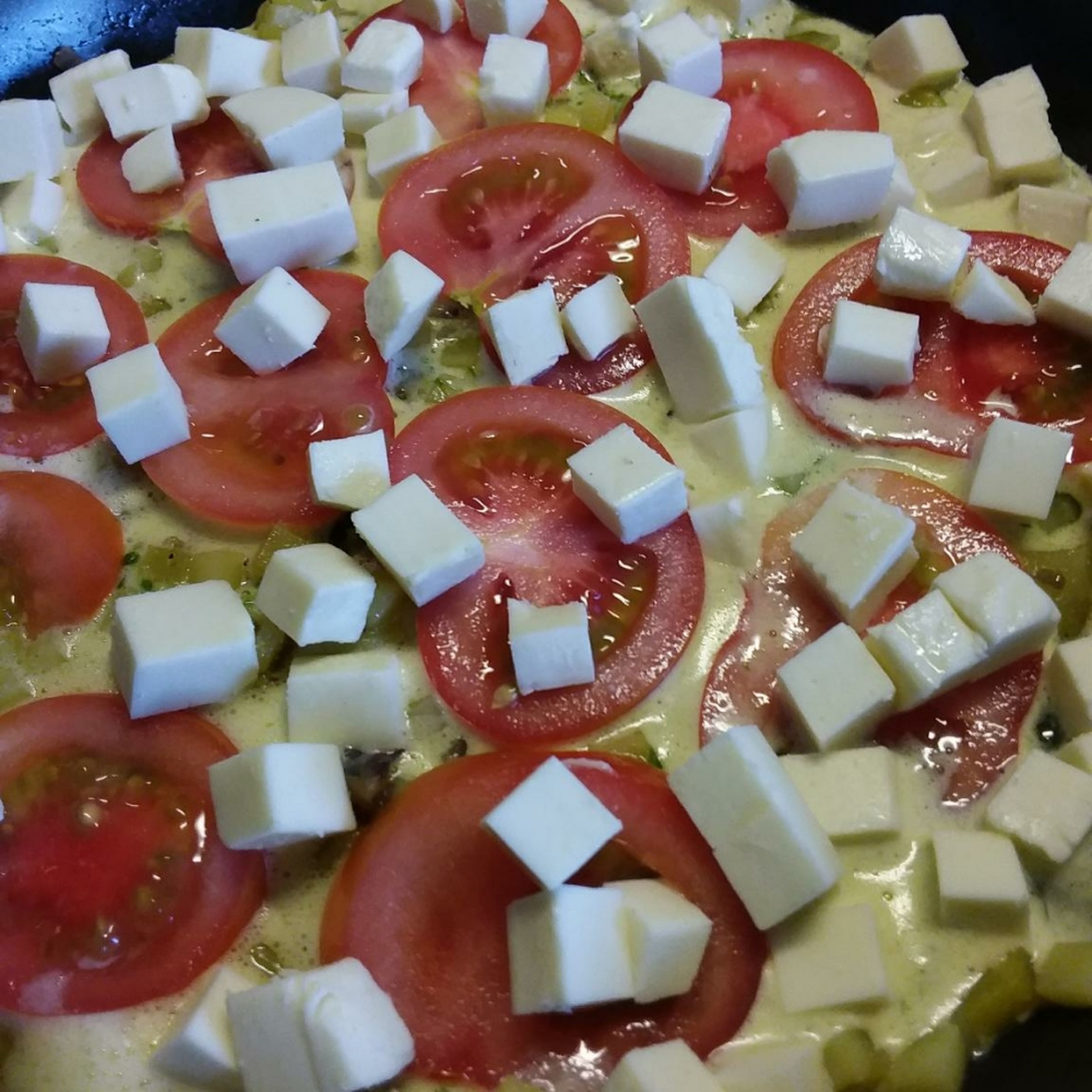 in Scheiben geschnittene Tomaten und gewürfelten Mozzarella auf dem Ganzen verteilen