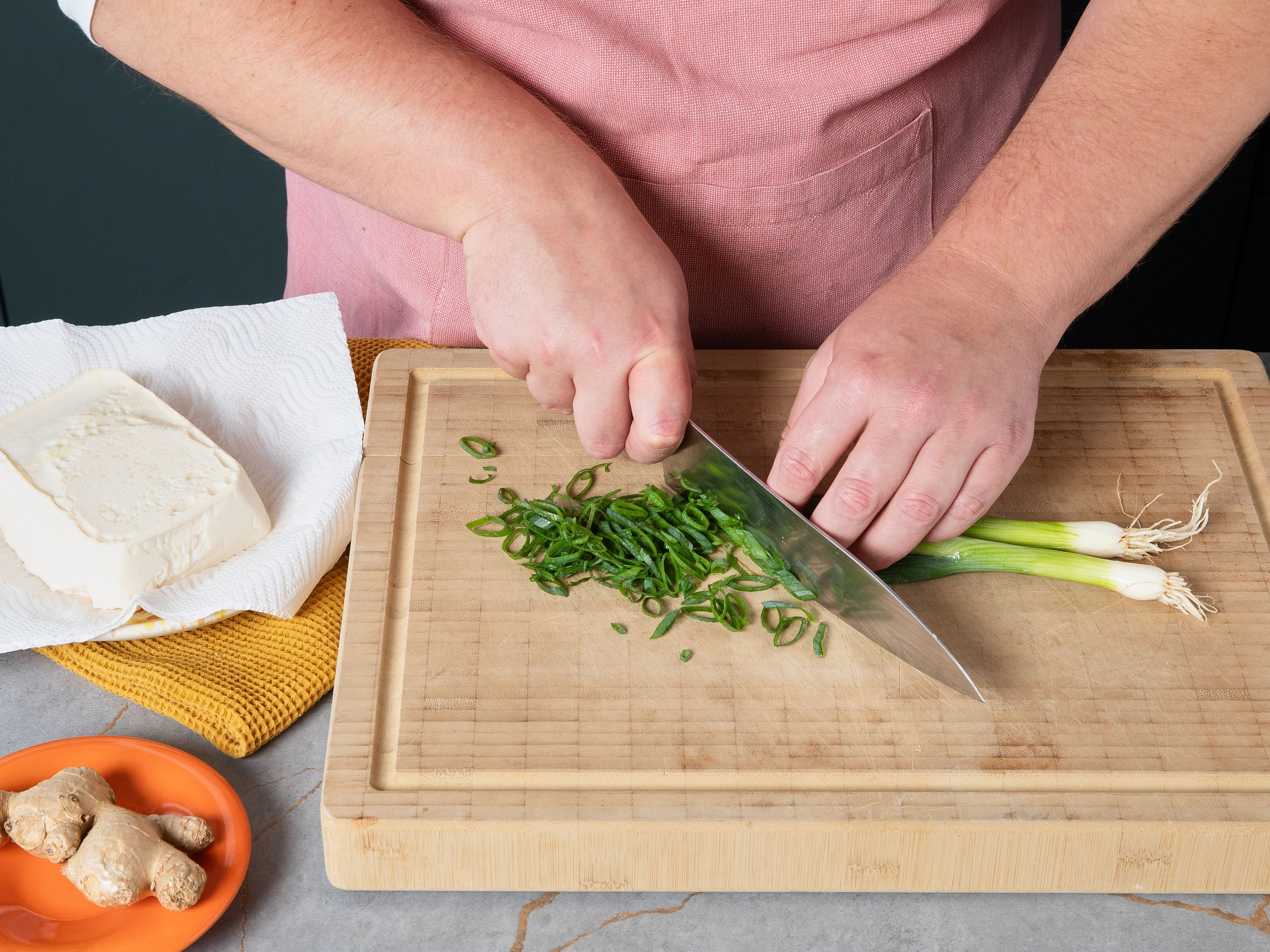 Den Seidentofu vorsichtig aus der Verpackung nehmen, überschüssiges Wasser abgießen und für ca. 10–15 Min. auf Küchenpapier abtropfen lassen. Die Frühlingszwiebeln in feine Ringe schneiden und sofort in Eiswasser geben. Den Ingwer schälen und fein reiben.
