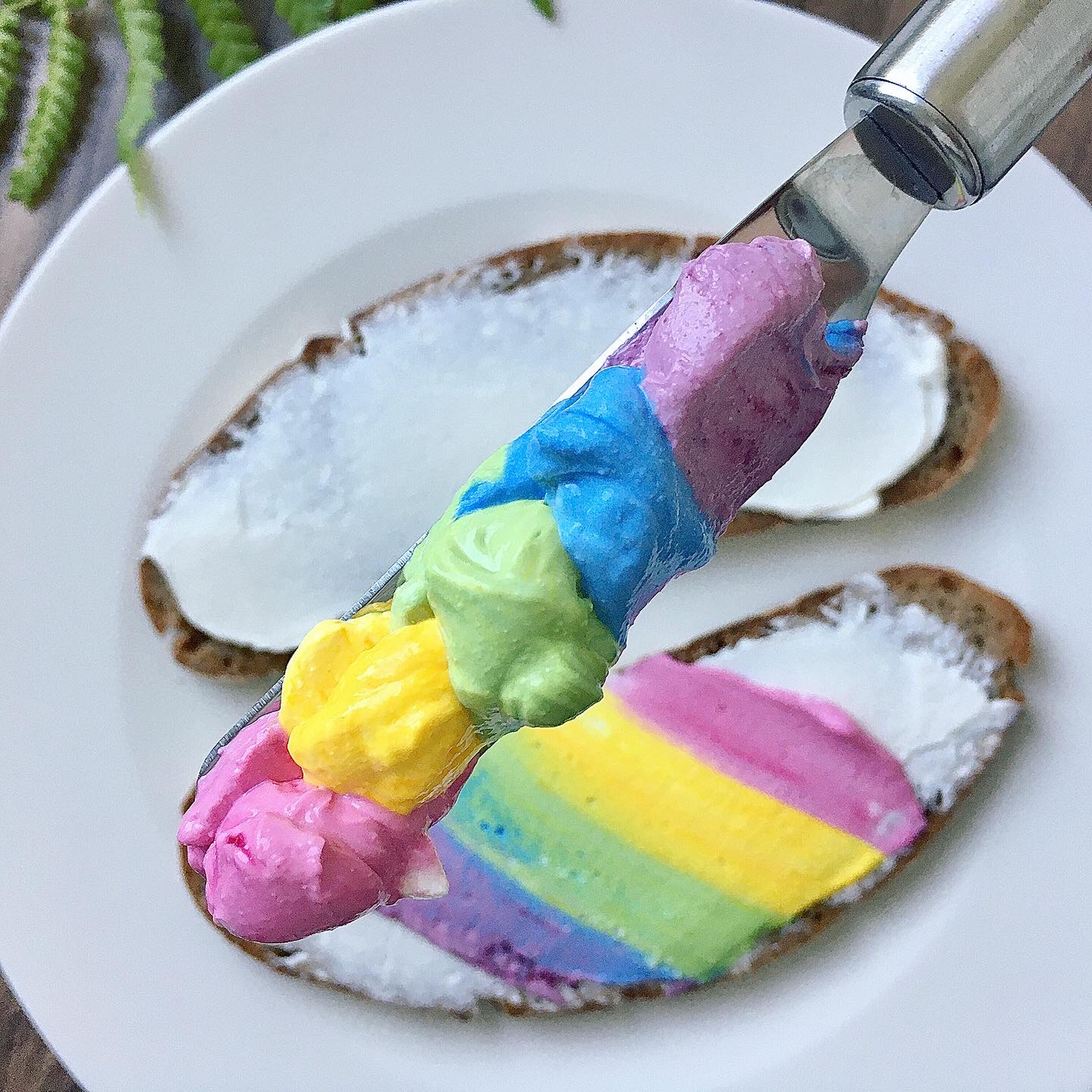 Verteilt von jeder Farbe einen Klecks nebeneinander auf ein Messer und streicht den Regenbogen auf euer Brot (meins ist ein Roggenbrot)