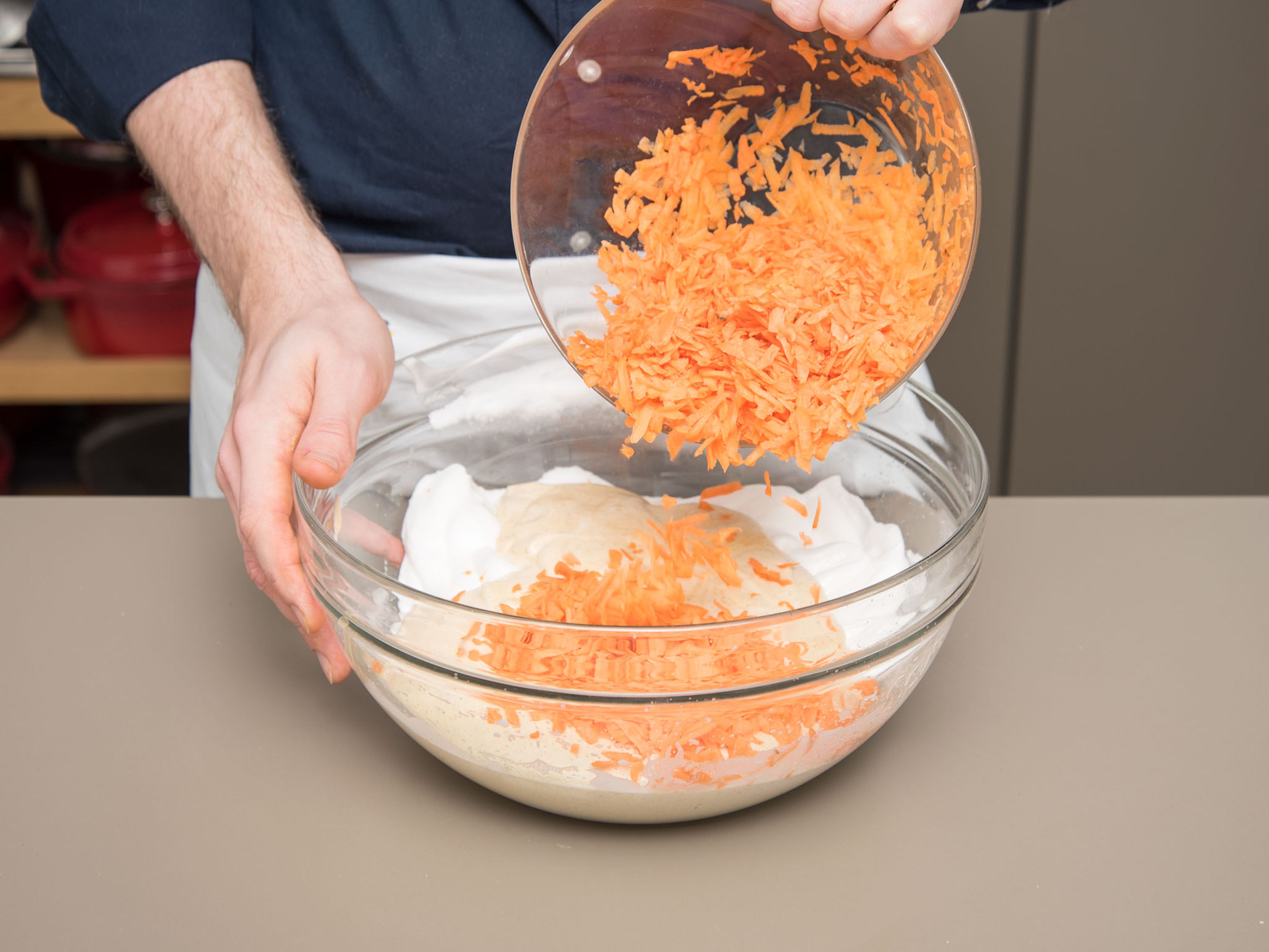 Geschlagene Eiweiße unter die Marzipan-Mischung heben. Danach die Mehl-Haselnuss-Mischung und die geriebenen Karotten unterheben.