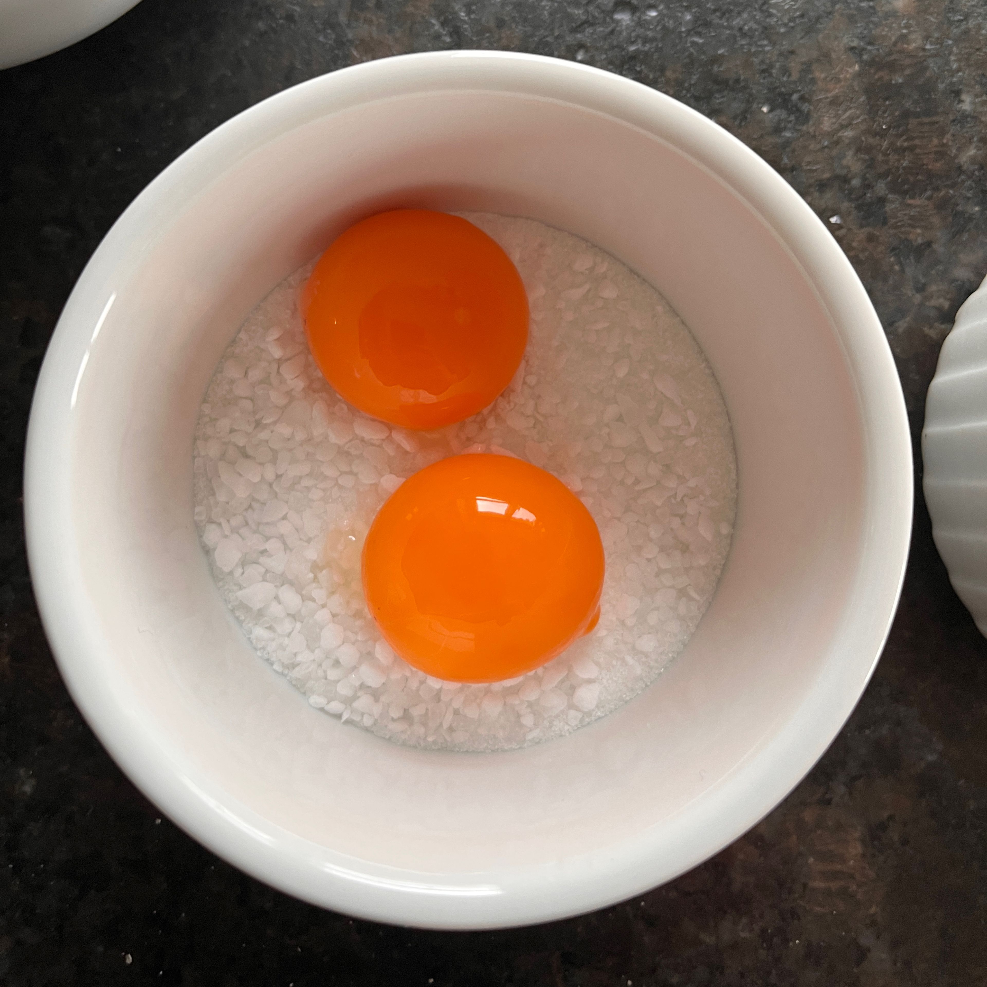 Das Ei trennen und das Eigelb vorsichtig in die Schüssel mit der Salz-Zucker-Mischung legen.